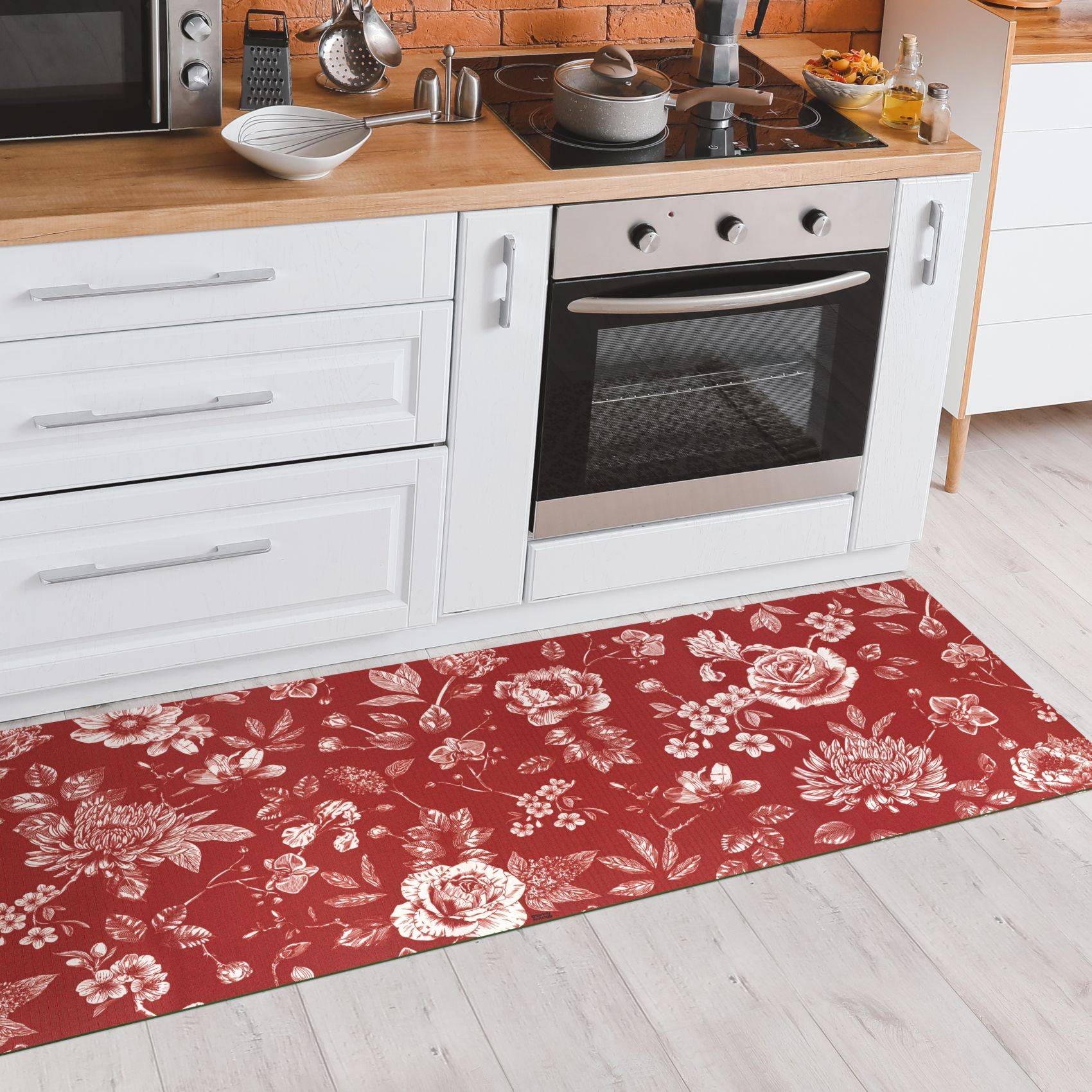 Rote Küchenunterlage mit Blumenmuster vor einem Ofen und weißen Schränken.