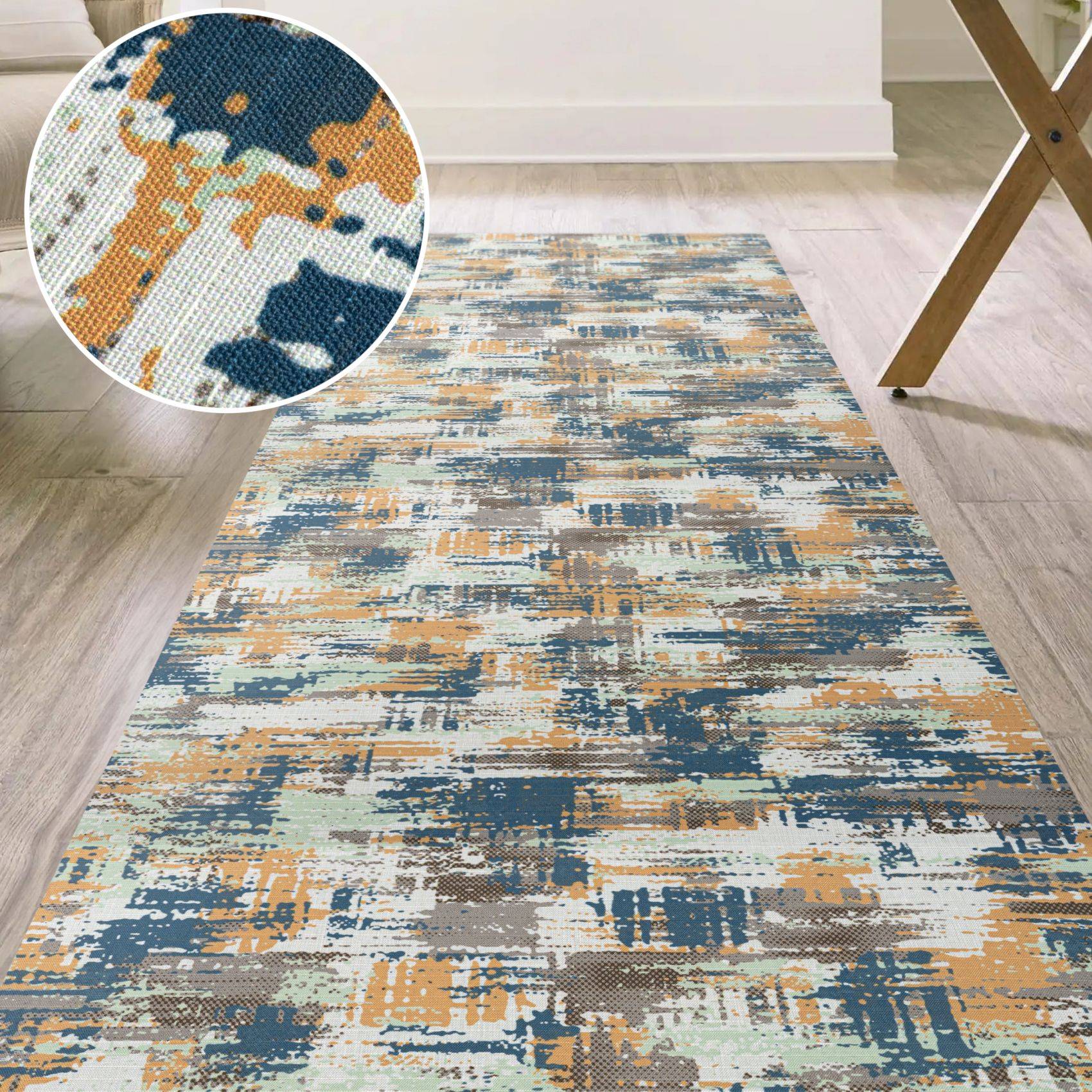Rechteckiger abstrakter Bereich Teppich mit blauem, grauem, creme- und goldfarbenem Pinselstrichmuster in einem hellen Raum, gezeigt mit einer Nahaufnahme der gewebten Textur.