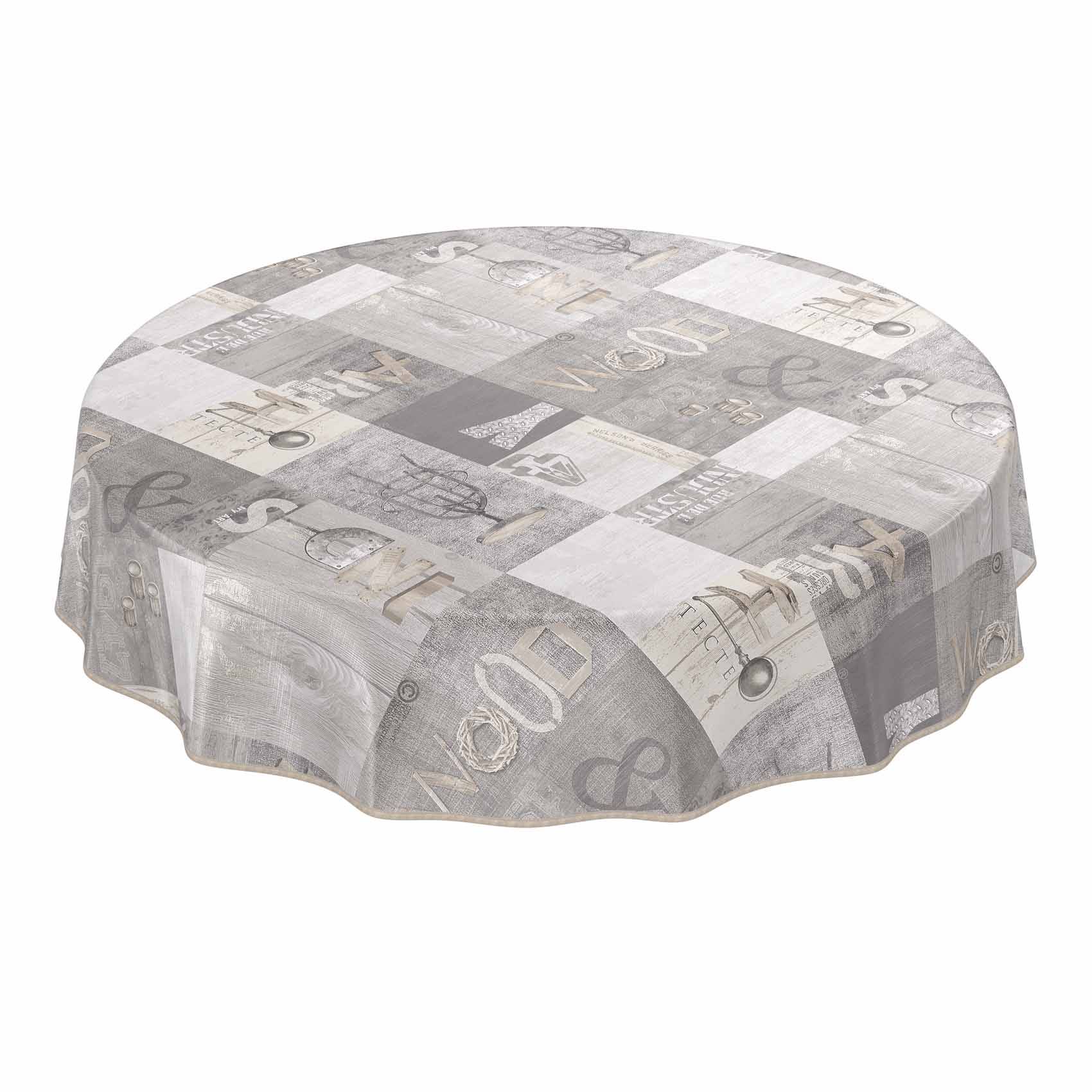 Runder Tisch mit einer grauen Patchwork-Tischdecke mit Mustern, die Buchstaben und dekorative Drucke zeigt.