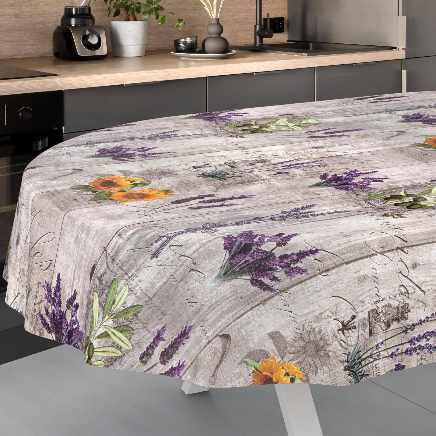 Tischdecke mit Blumenmuster auf einem Esstisch in einer modernen Küche, mit violetten und gelben Blumen auf einem hellem Holzmaserungshintergrund.