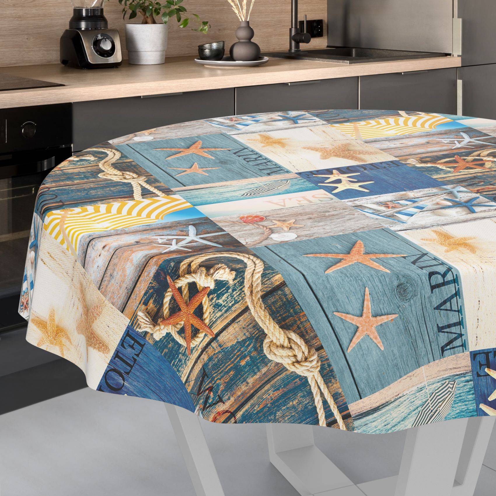 Rechteckiger Tisch mit einer Tischdecke mit Seemuster, die Seesterne, Seile und Holzbrettmuster in Blau, Beige und Gelb aufweist.