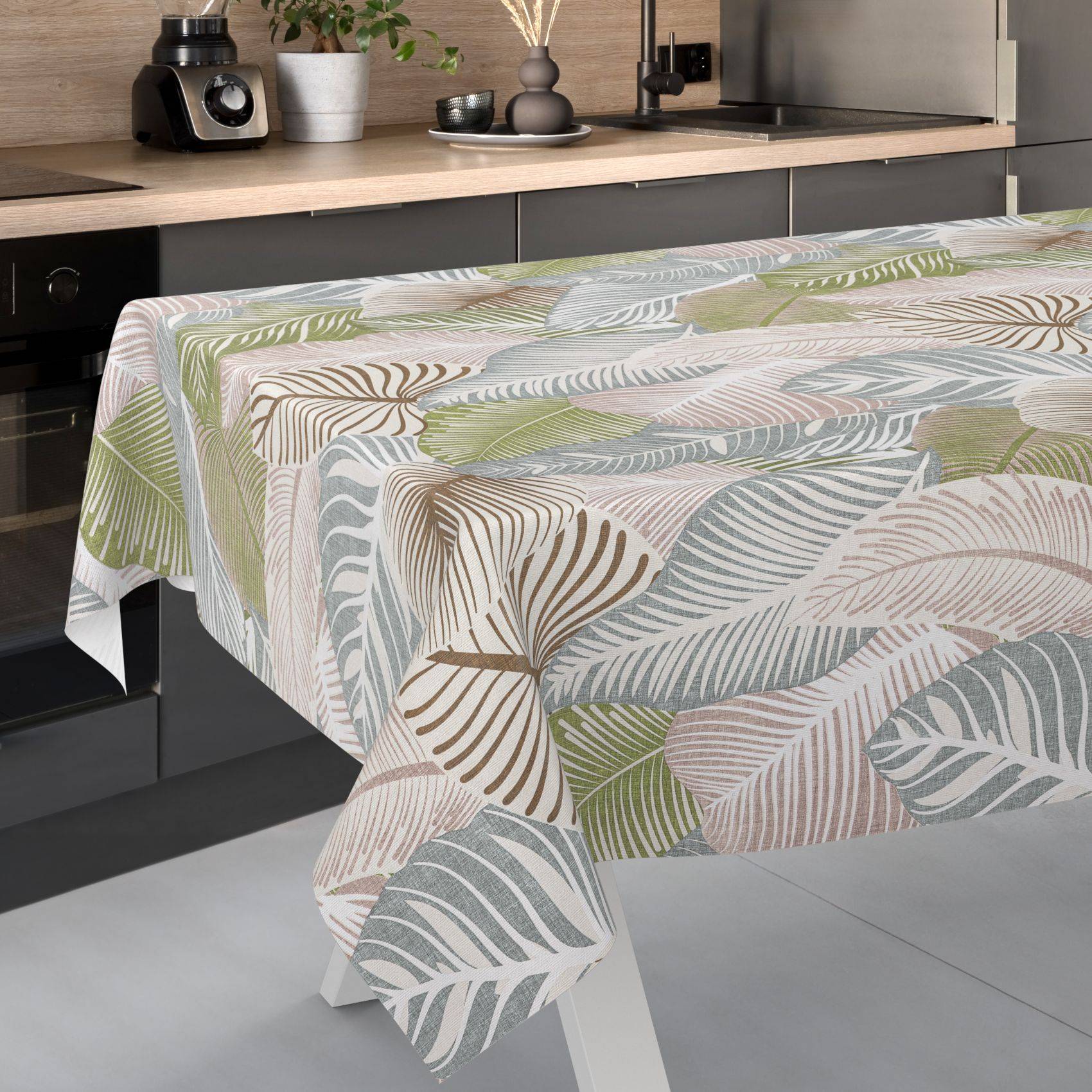 Gemusterte Tischdecke mit pastellfarbenen Blatt- und Federnmotiven, über einen Esstisch in einer modernen Küche drapiert