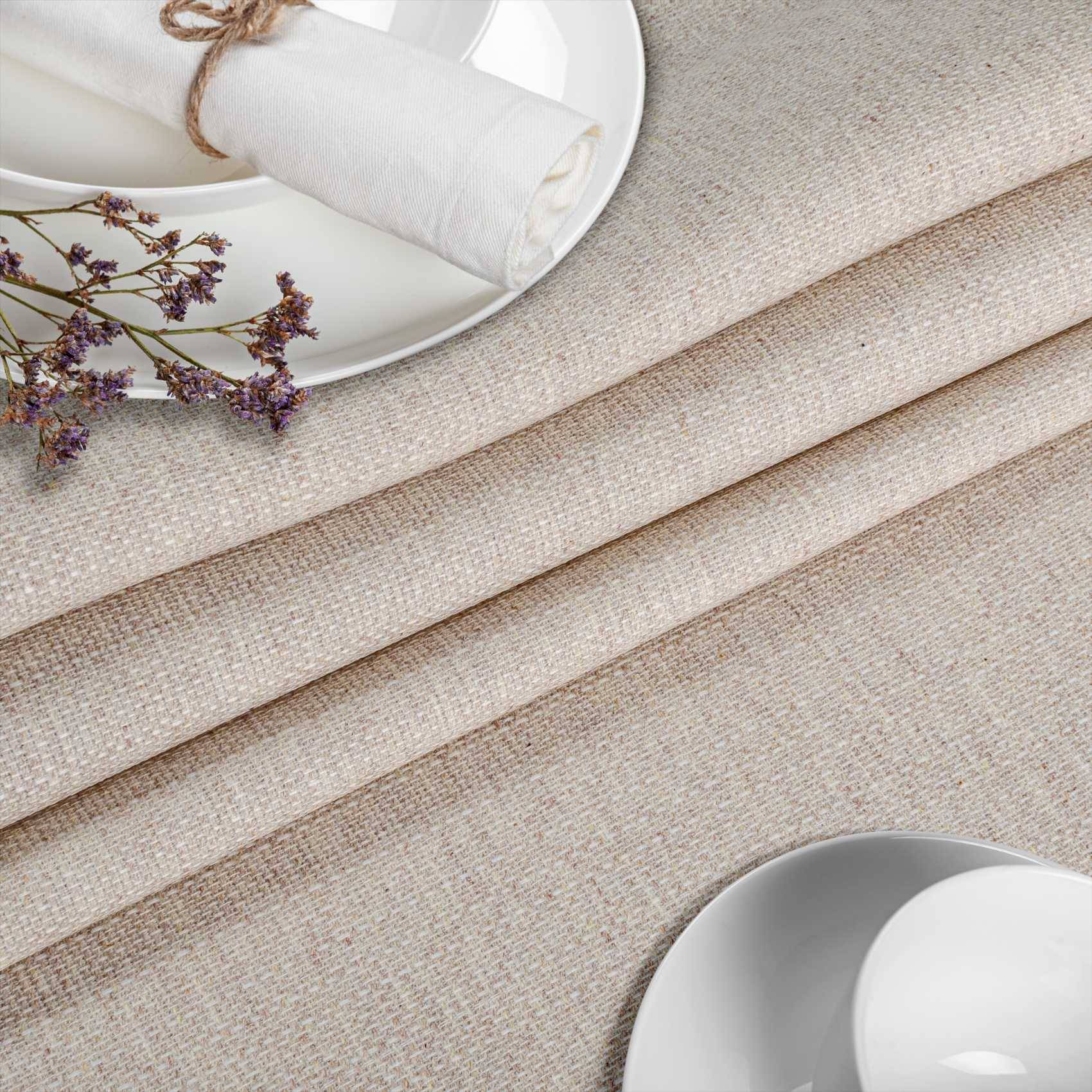 Beige strukturierter Stoff mit einer gefalteten Serviette auf einem weißen Teller und getrockneten Blumen, gezeigt als neutraler Wohndekor oder Tischdeckungshintergrund.