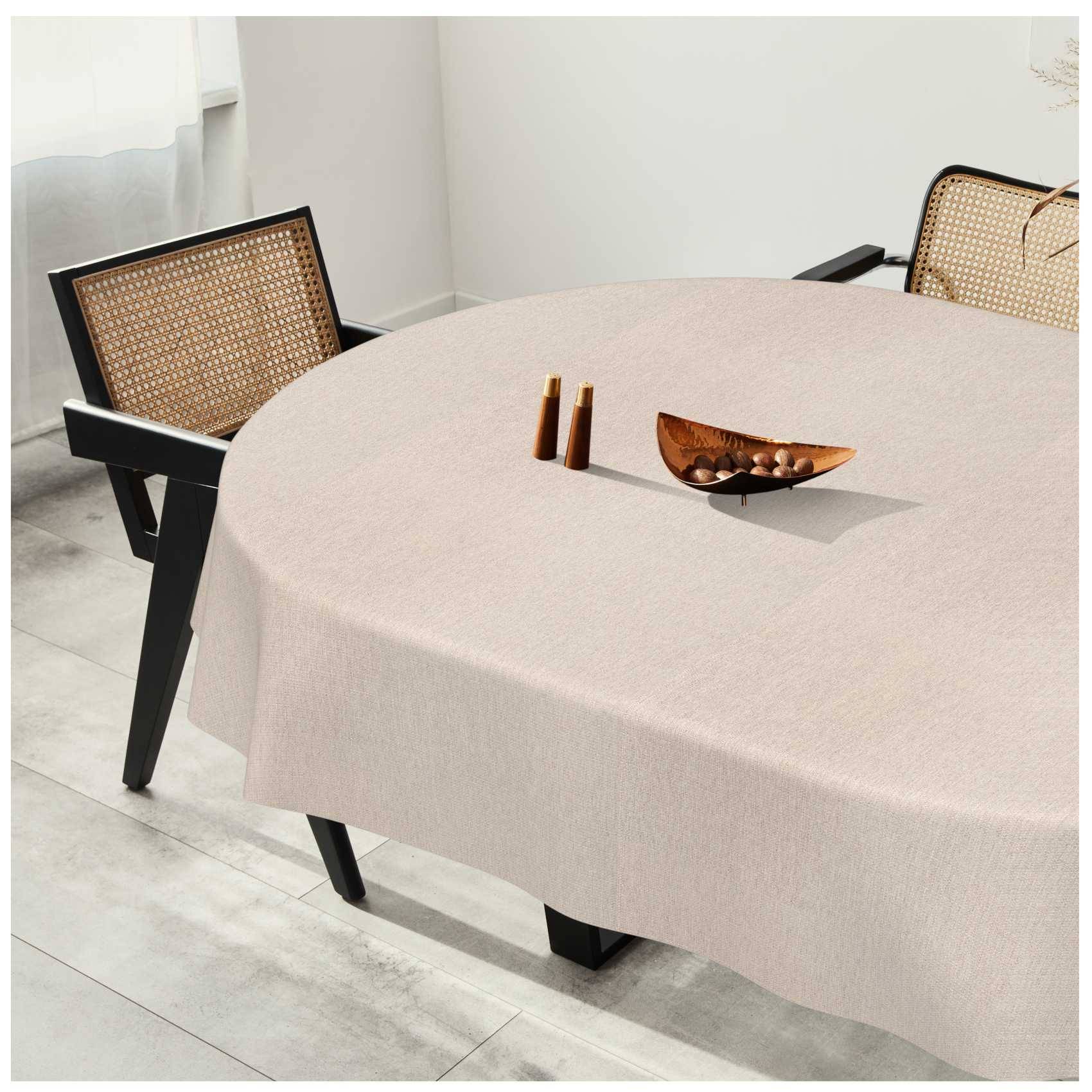 Minimalistischer Esstisch mit beigefarbenem Tuch, zwei Stühlen mit Rohrgeflecht-Rückenlehne und einer kleinen Holzschale sowie Salz- und Pfefferstreuern in einem hellen Raum.
