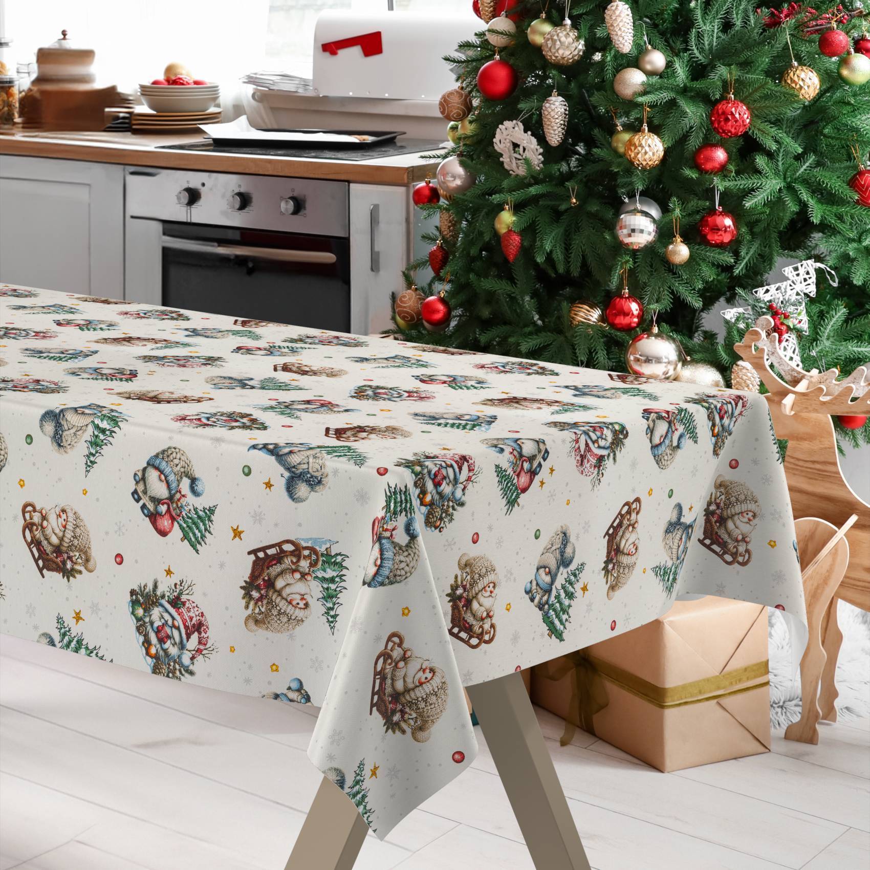 Weihnachtlicher Esstisch mit festlicher Tischdecke, dekoriertem Baum, Rentier-Dekoration und verpacktem Geschenk in einer hellen Küche