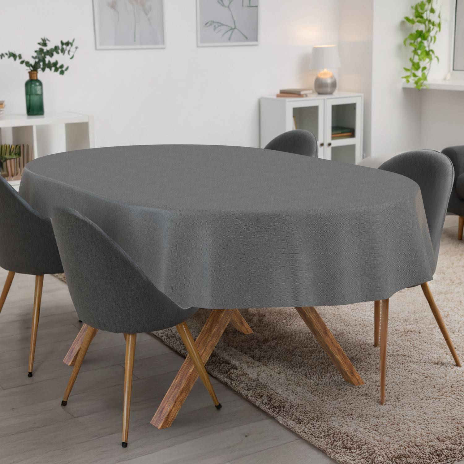 Esstisch mit grauer Tischdecke in einem hellen, modernen Wohnzimmer mit vier Stühlen und einem Teppich.