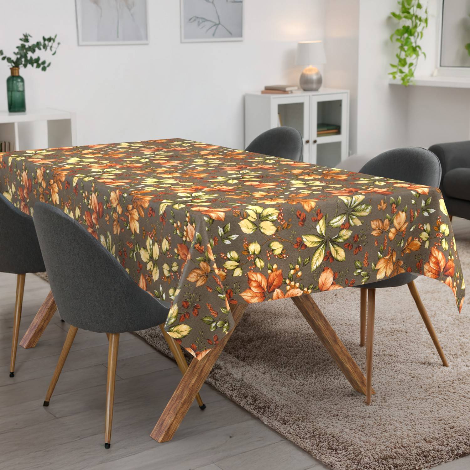 Esstisch mit einer braunen Tischdecke mit Herbstlaubmuster in einem modernen Wohnzimmer mit dunklen Stühlen und einem Teppich.