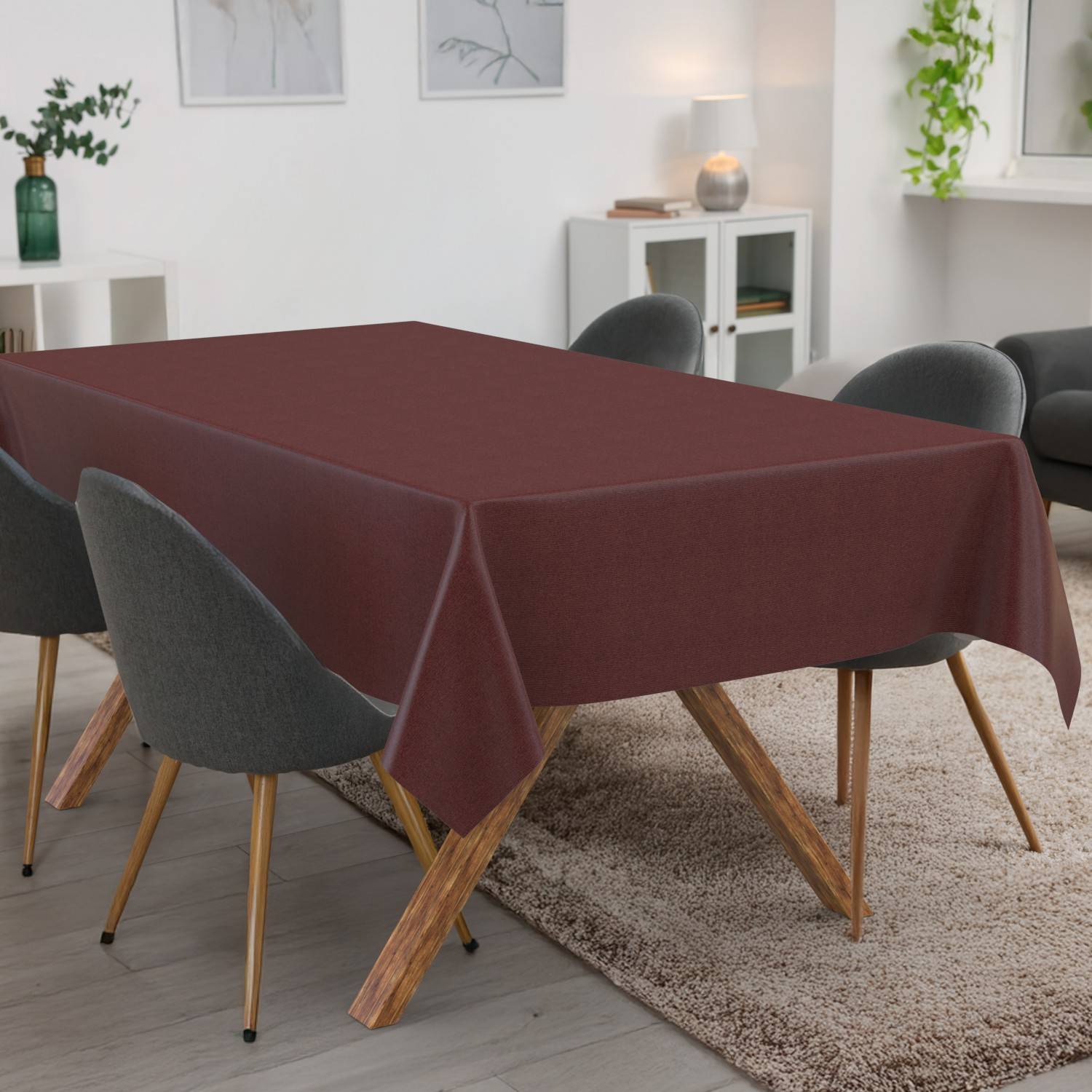 Ein Esstisch mit einer burgunderfarbenen Tischdecke ist von grauen Stühlen in einem modernen Wohnzimmer umgeben.