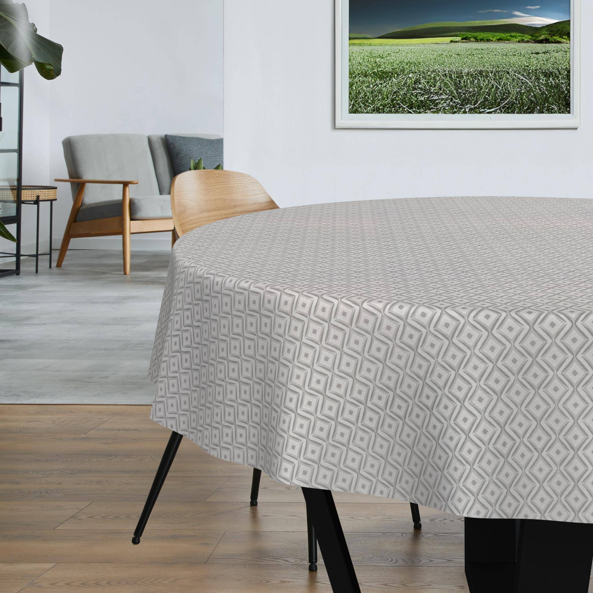 Ein runder Tisch mit einer hellgrauen geometrisch gemusterten Tischdecke in einem modernen Zimmer mit Stühlen und gerahmten Wandbildern.
