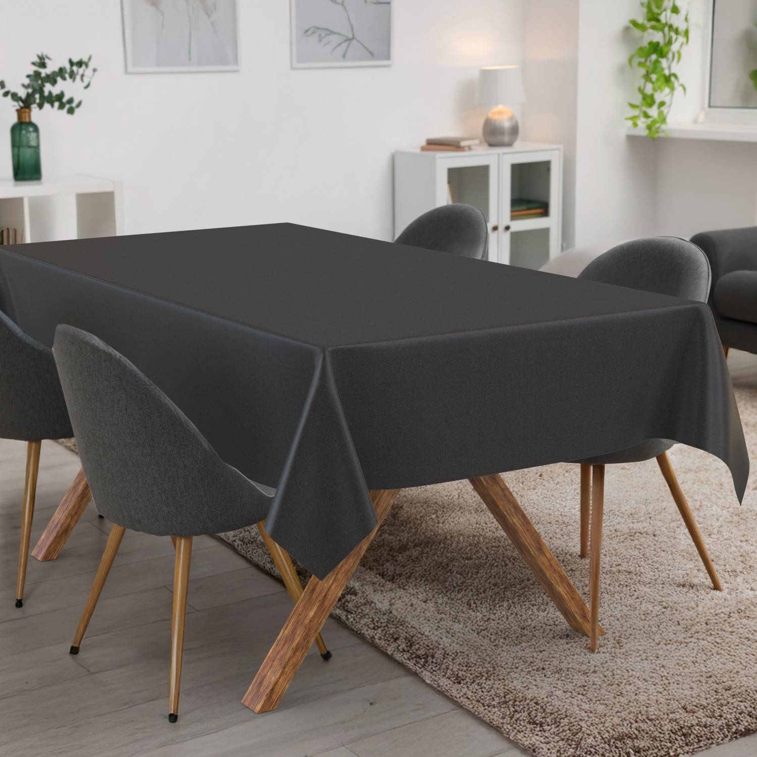 Esstisch mit schwarzer Tischdecke in einem modernen Raum, umgeben von grauen Stühlen auf einem Teppich.