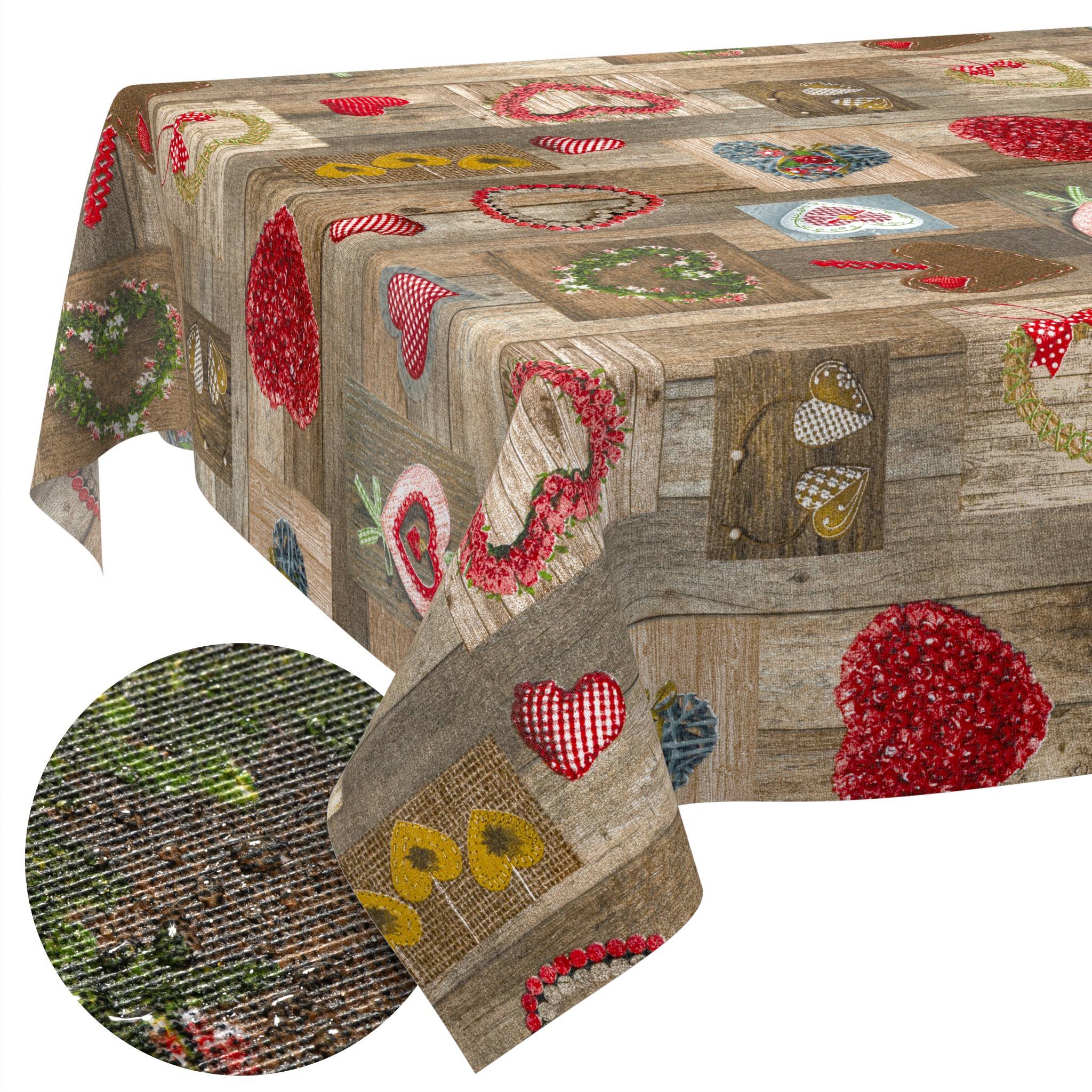 Rustikales Patchwork-Tischtuch mit Herz- und Blumenmotiven in Rot, Rosa, Gelb und Grün auf einem Stoff mit Holzoptik.