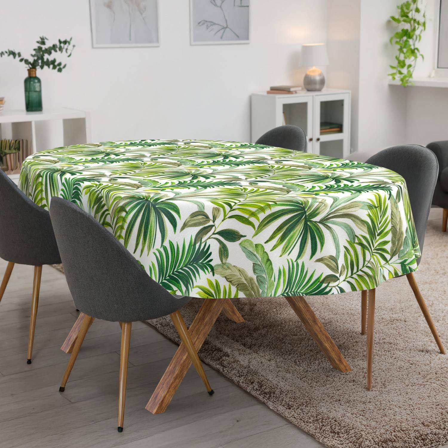 Esstisch mit einer grünen Tischdecke mit tropischem Blattmuster, umgeben von grauen Stühlen in einem hellen modernen Raum.