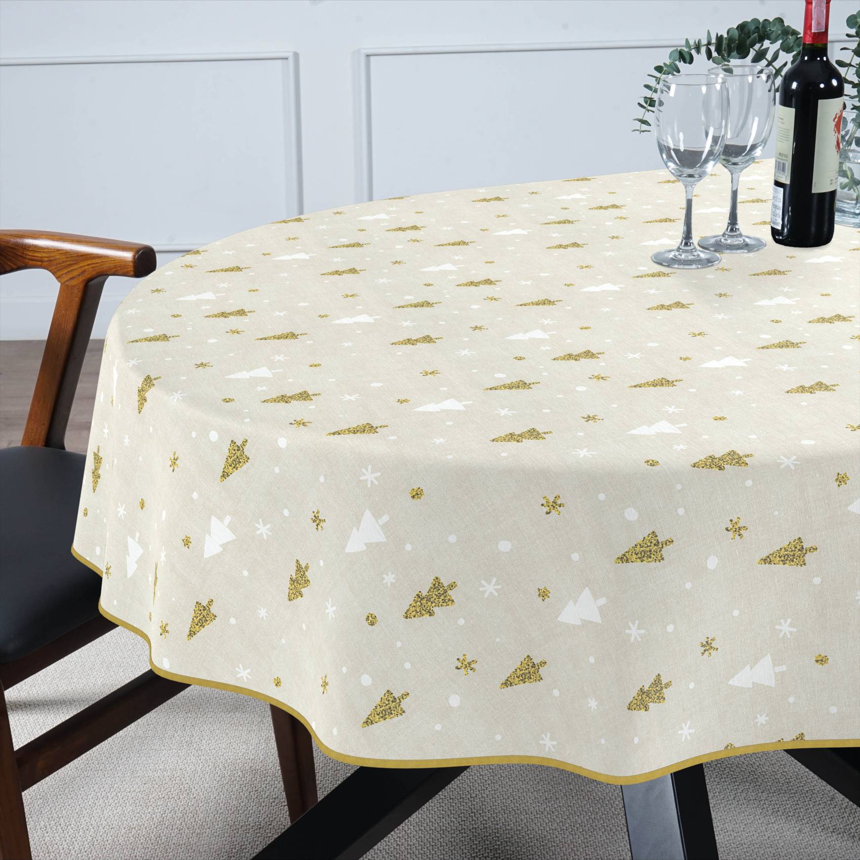 Runder Esstisch mit cremefarbener Tischdecke mit goldenem und weißem Baummuster, eingedeckt mit Weingläsern und einer Flasche in einem modernen Esszimmer.