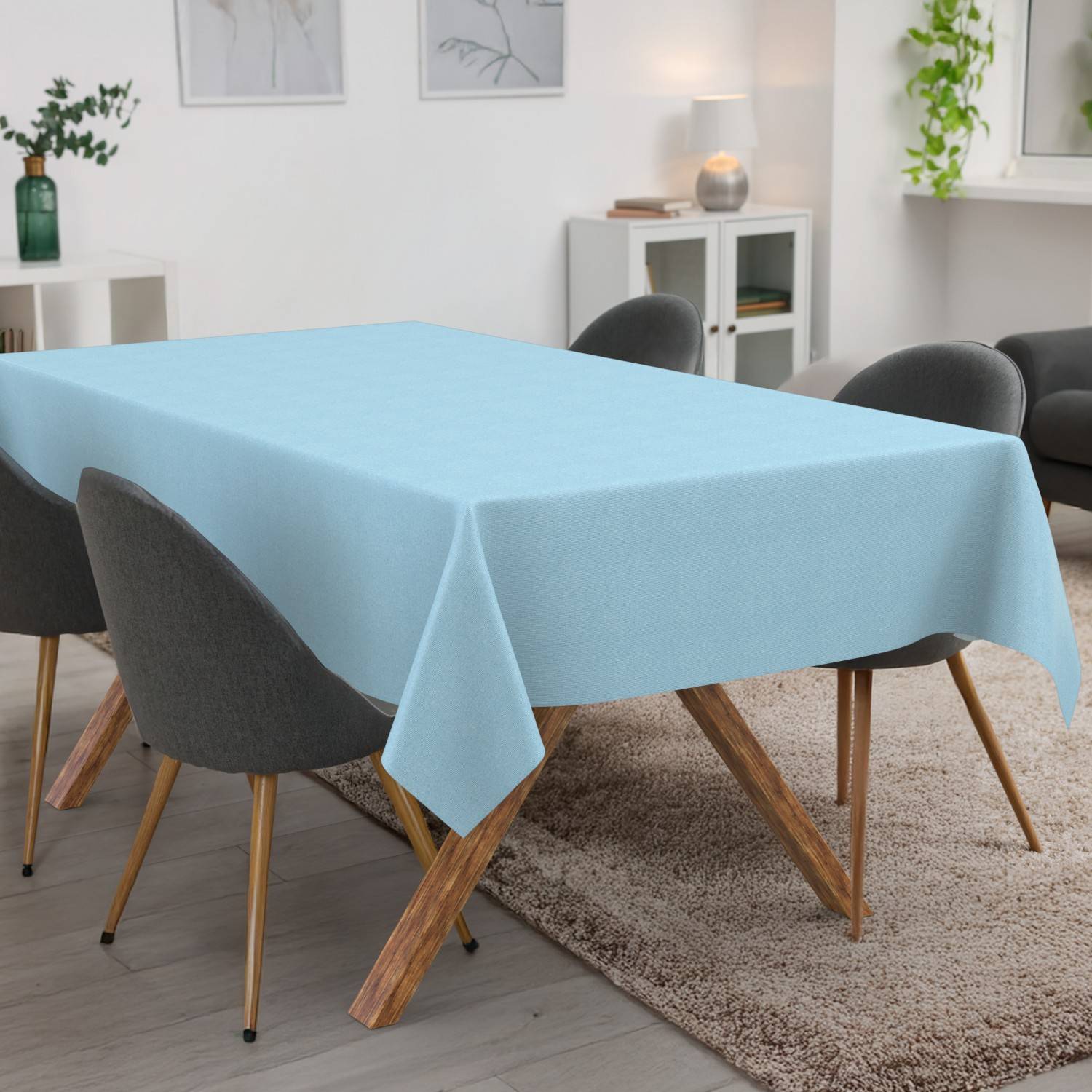 Ein rechteckiger Esstisch mit einer hellblauen Tischdecke in einem modernen Esszimmer mit grauen Stühlen.