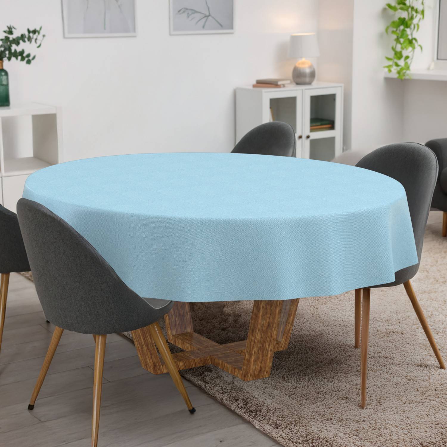 Hellblaue runde Tischdecke auf einem Esstisch, umgeben von vier grauen Stühlen in einem hellen modernen Raum.