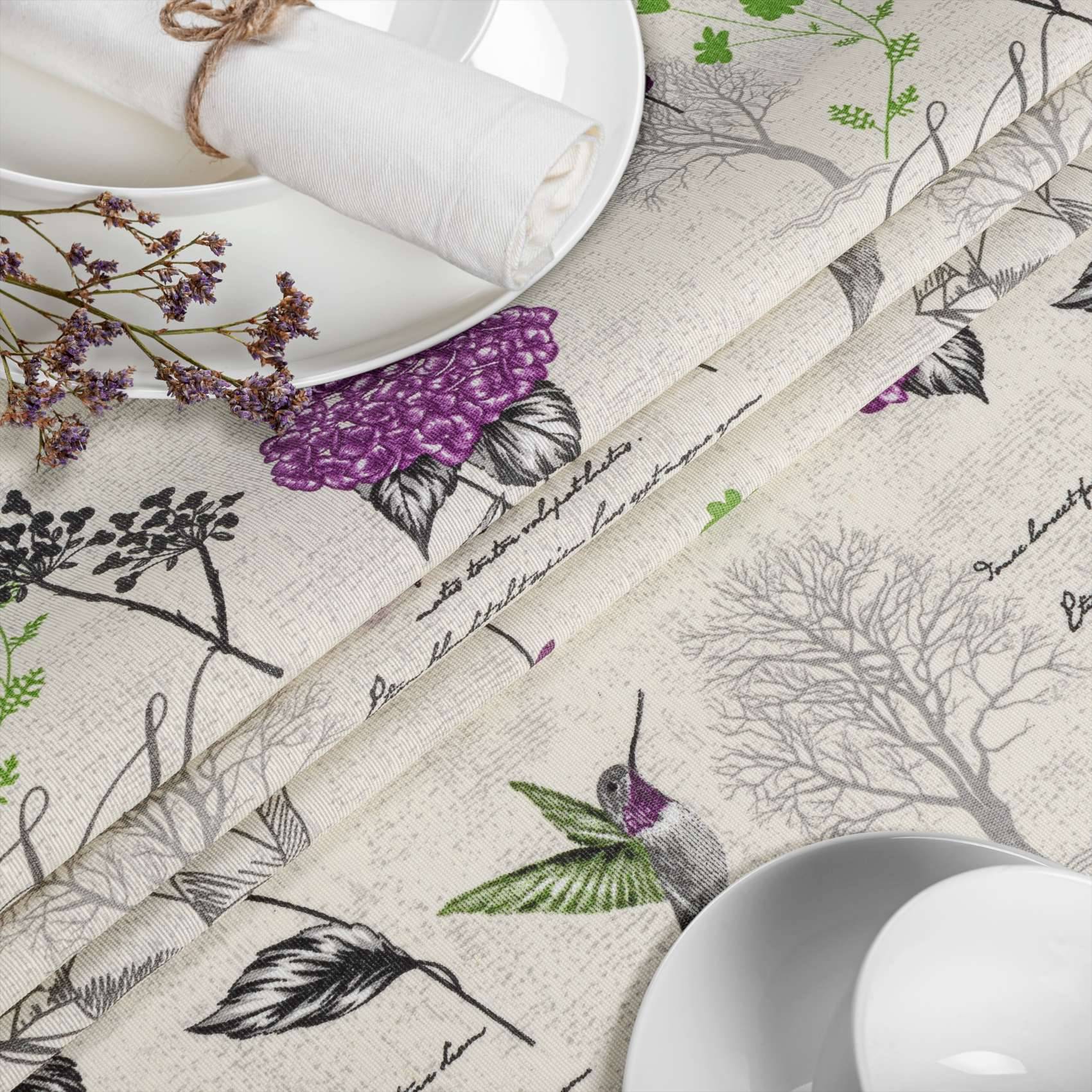 Gemusterte Tischdecken mit botanischem Druck und Kolibri-Design, gezeigt mit weißen Tellern, Servietten und getrockneten Blüten.