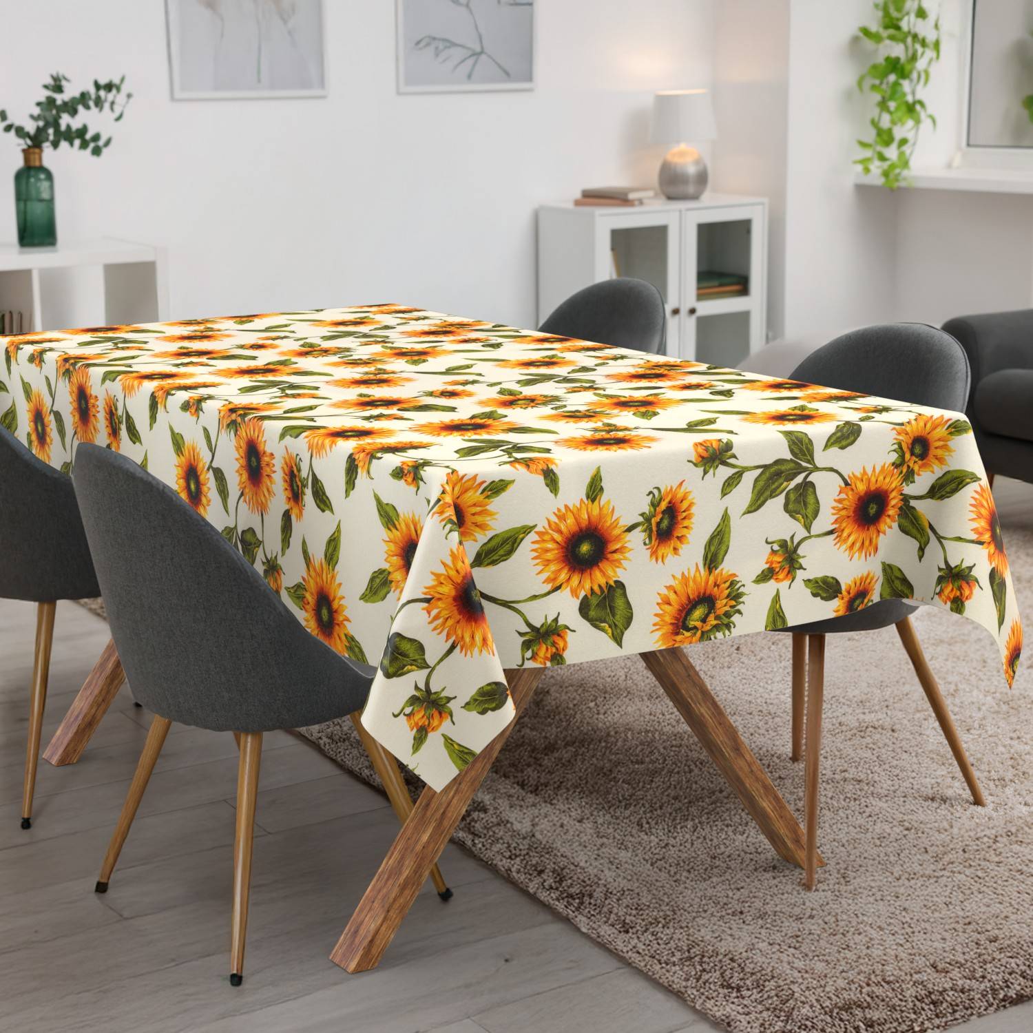 Esstisch mit einer Tischdecke im Sonnenblumenmuster in einem modernen Wohnzimmer mit dunklen Stühlen und einem beigefarbenen Teppich.