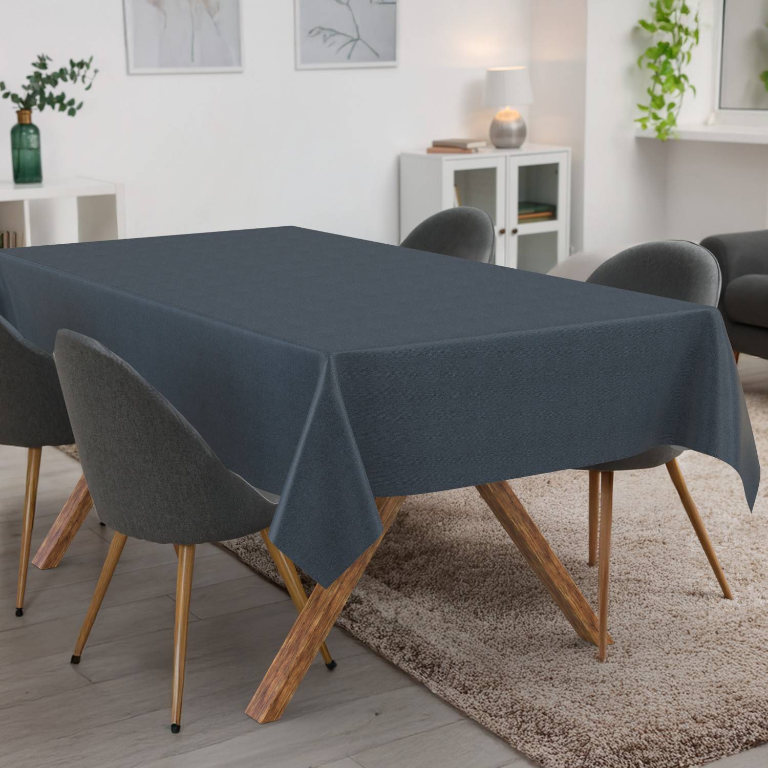 Esstisch mit dunkelgrauer Tischdecke in einem modernen Wohnzimmer, umgeben von gepolsterten Stühlen auf einem Teppich.