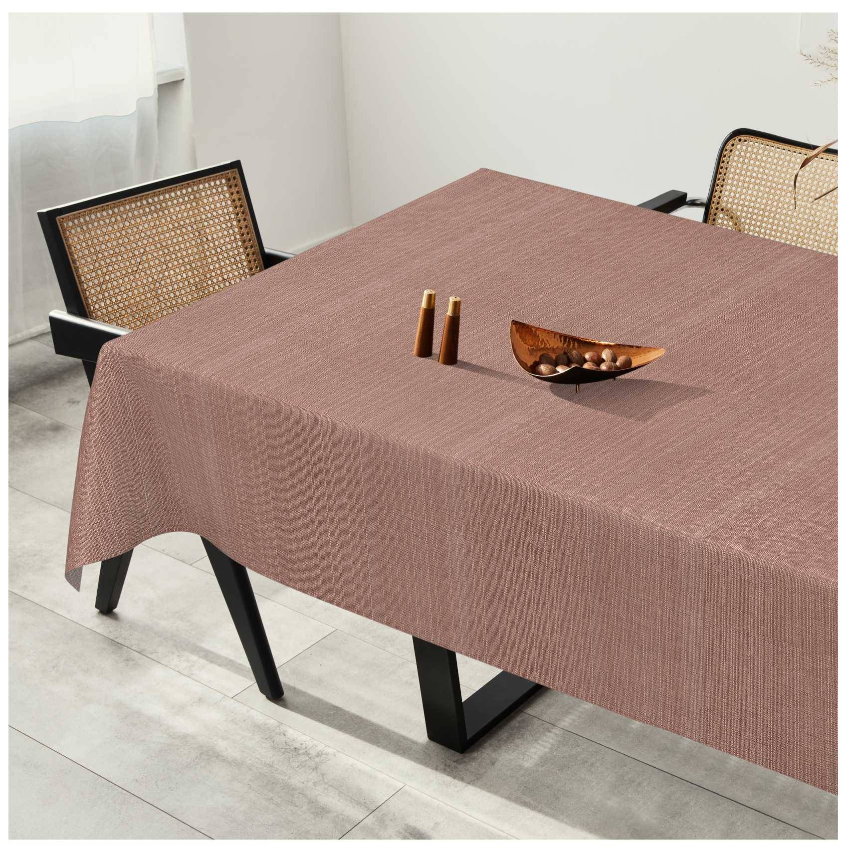 Esstisch mit einer braunen Tischdecke, zwei Stühlen mit Flechtwerk-Rückenlehne und einer Holzschale sowie Salz- und Pfefferstreuern oben drauf in einem hellen Raum.