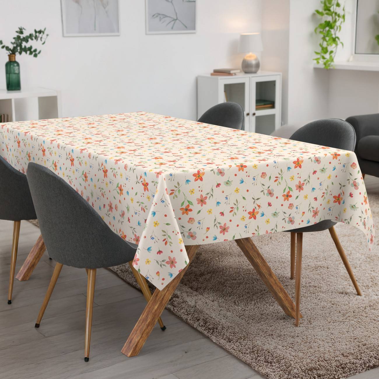 Tischdecke mit Blumenmuster, die über einen Esstisch in einem modernen Wohnzimmer mit Stühlen und einem Sofa drapiert ist.