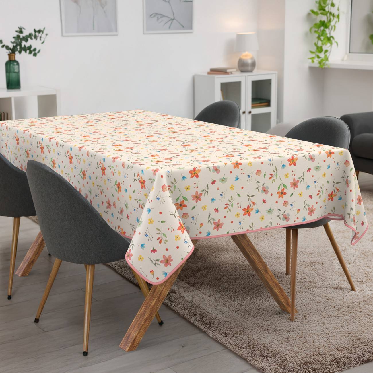 Tischdecke mit Blumenmuster, das über einen Esstisch in einem modernen Wohnzimmer mit vier grauen Stühlen drapiert ist.