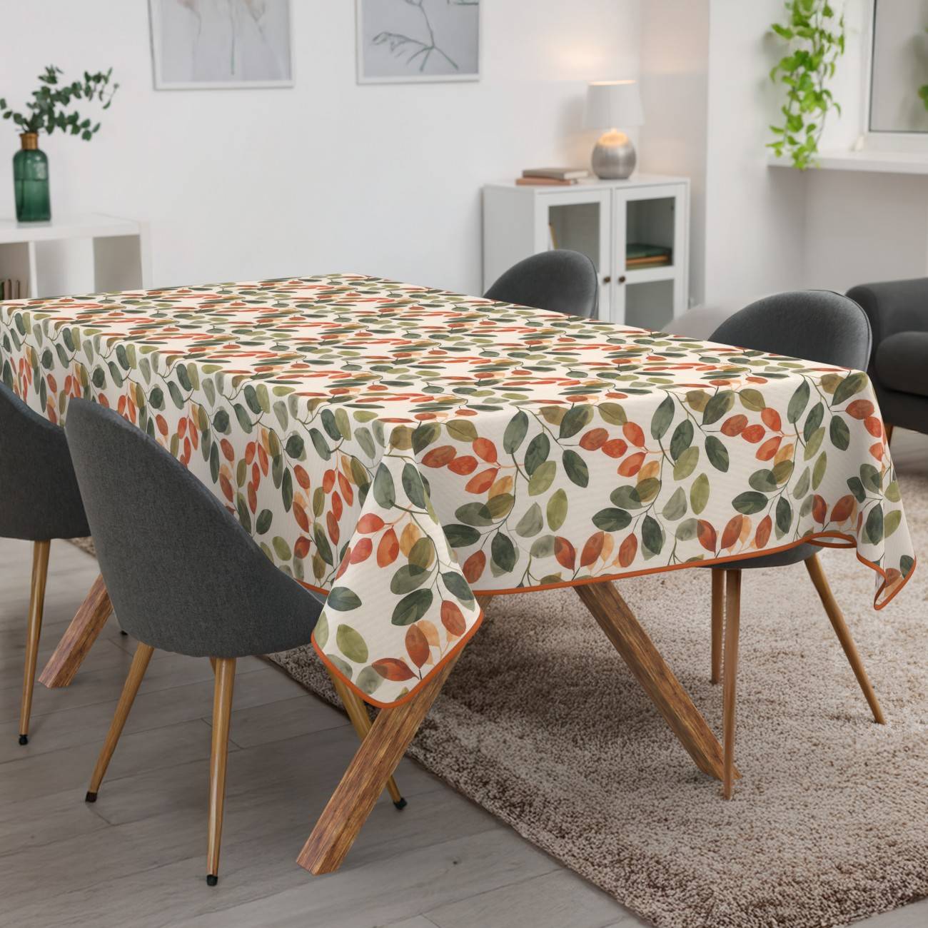Esstisch mit einer Tischdecke mit Blattmuster, umgeben von dunkel gepolsterten Stühlen in einem hellen modernen Wohnzimmer.