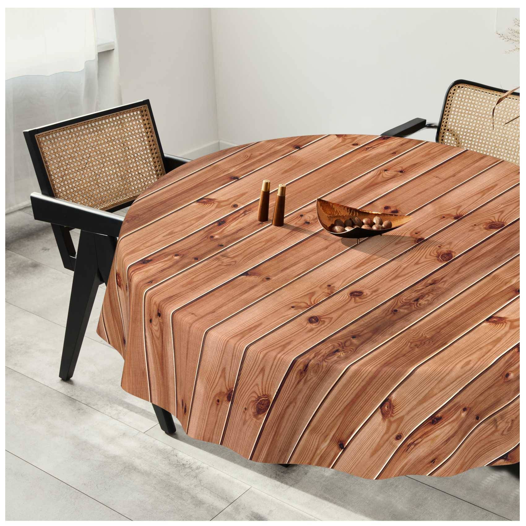 Runder Holzesstisch mit einer gestreiften Holzmaserung-Tischdecke, flankiert von zwei Stühlen mit Rohrgeflecht-Rückenlehne in einem hellen Raum.