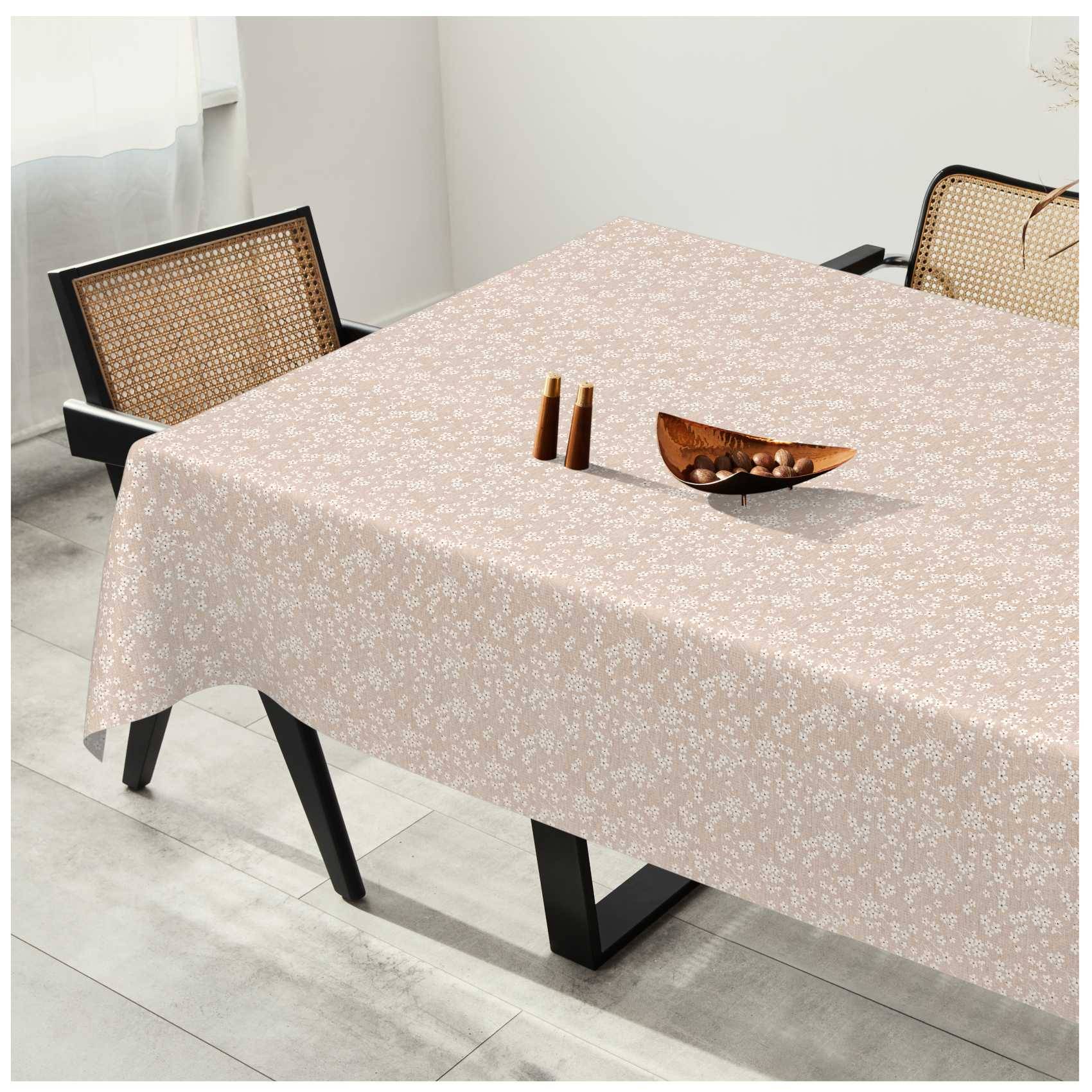 Esstisch mit hellem Blumenmuster-Tischtuch, zwei Stühlen mit Rattanrücken und einer Holzschale mit kleinen Dekorationsgegenständen in einem hellen Raum.