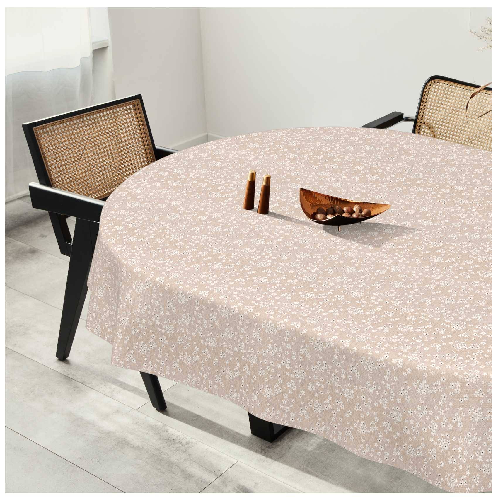 Esstisch mit einer hellrosa gemusterten Tischdecke, zwei Stühlen mit Rohrrückenlehnen und einer kleinen Holzschüssel sowie zwei Vasen darauf in einem hellen Raum.