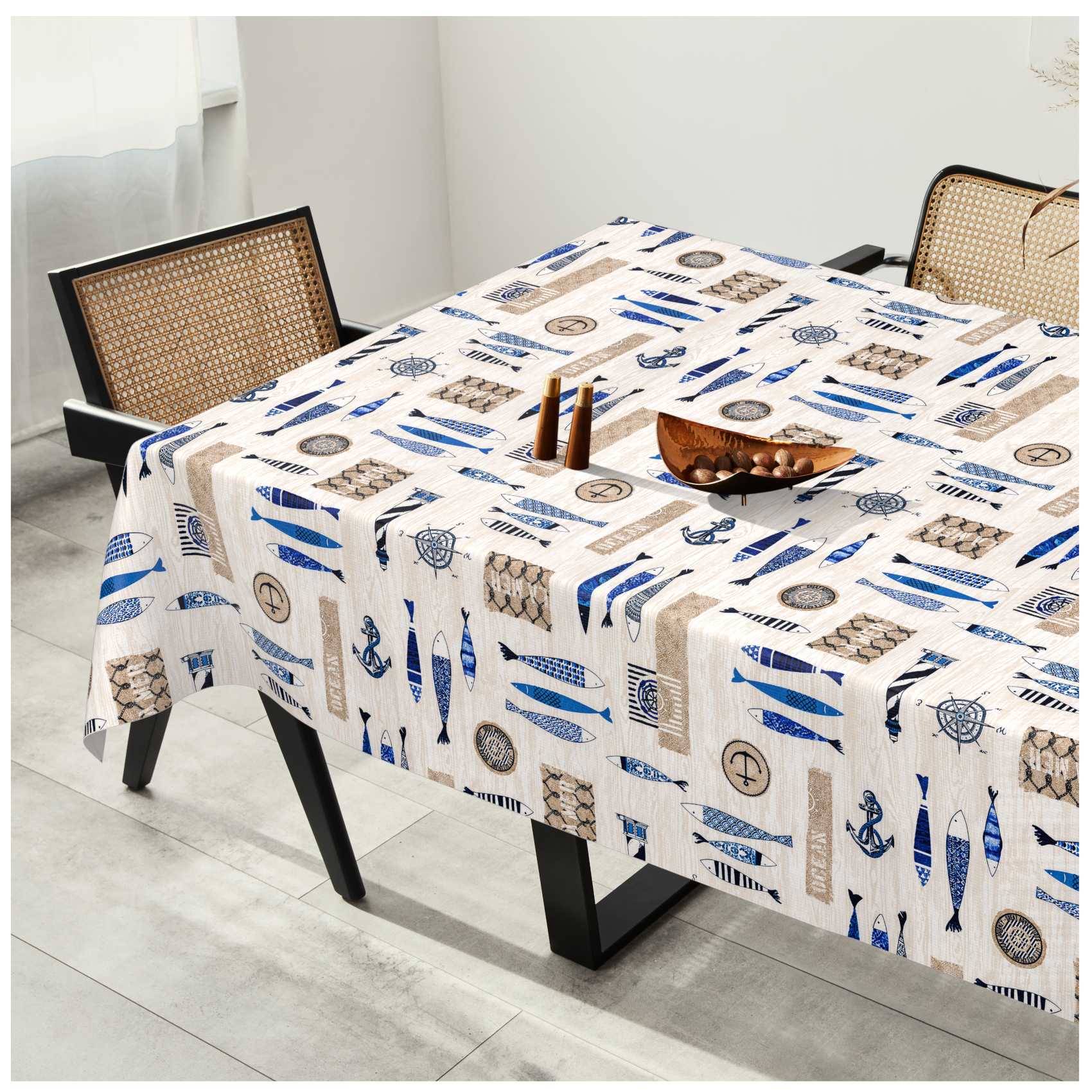 Esstisch mit einer weißen Tischdecke mit nautischem Muster, in einem hellen Raum mit Stühlen mit gewebtem Rücken und einer kleinen dekorativen Tischmitte aufgestellt.