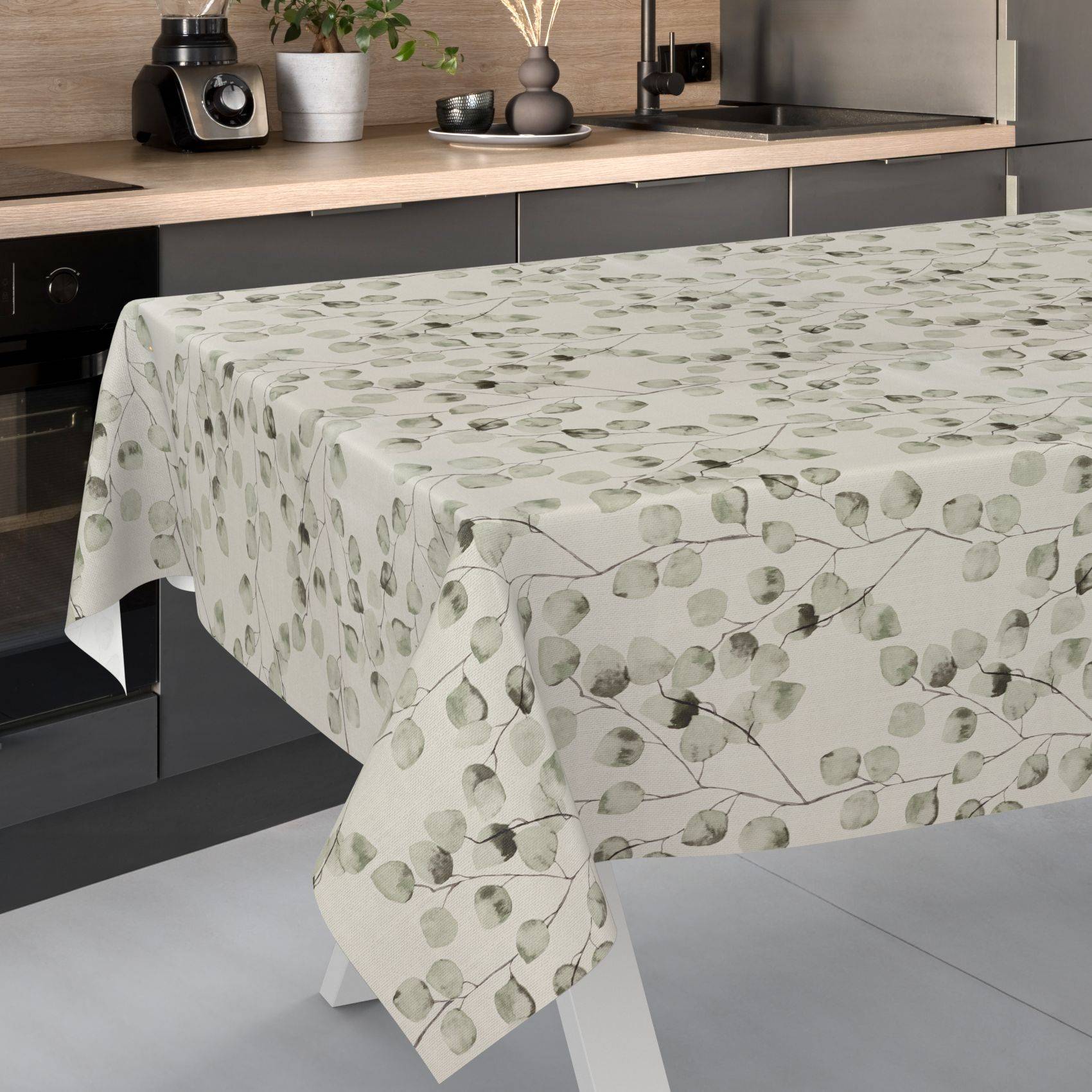 Rechteckiger Esstisch mit einer hellbeigen Tischdecke mit Blattmuster in einer modernen Küche.