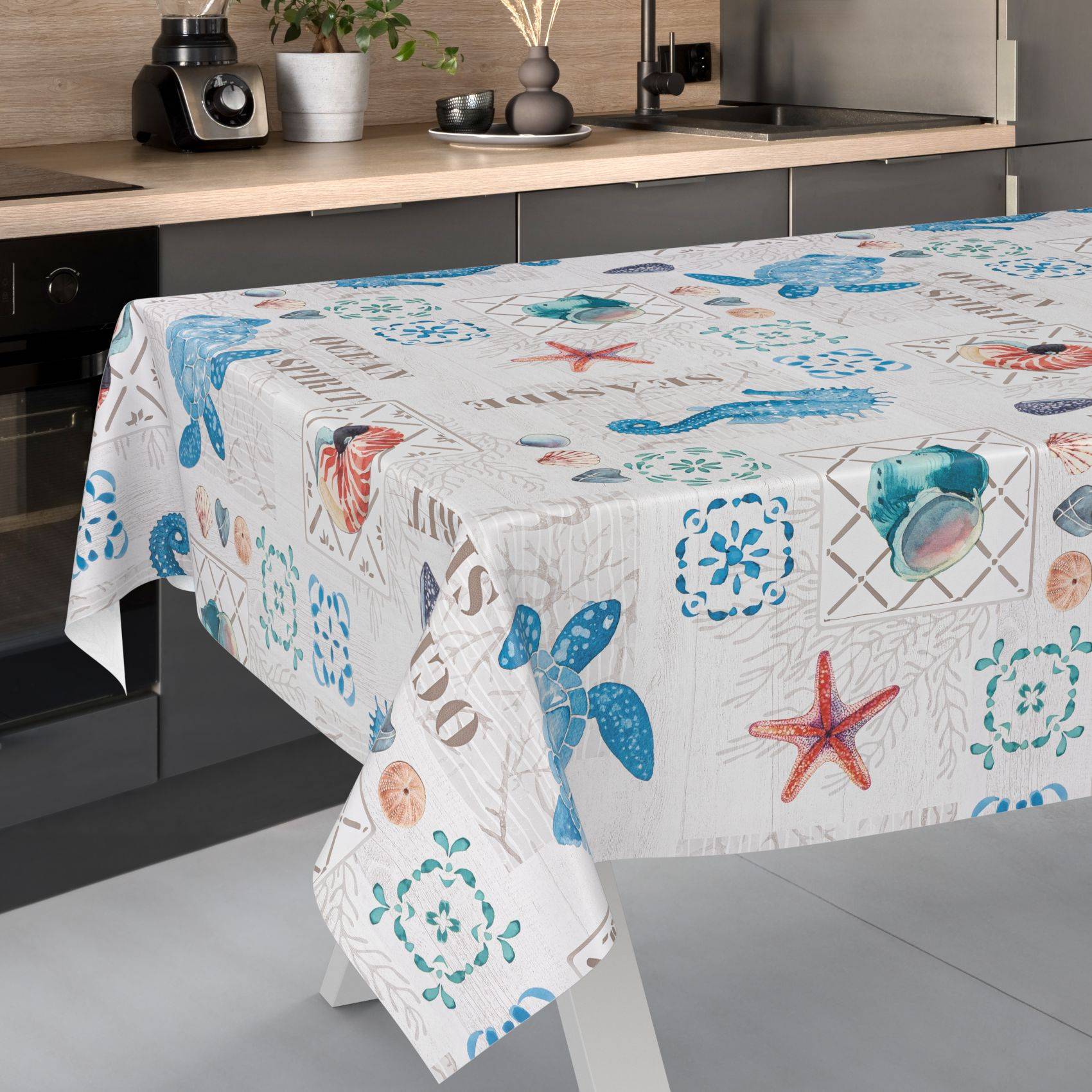 Ein Tisch mit einer weißen, ozeanischen Tischdecke, die blaue Seesterne, Muscheln und Korallenmuster in einer modernen Küche aufweist.