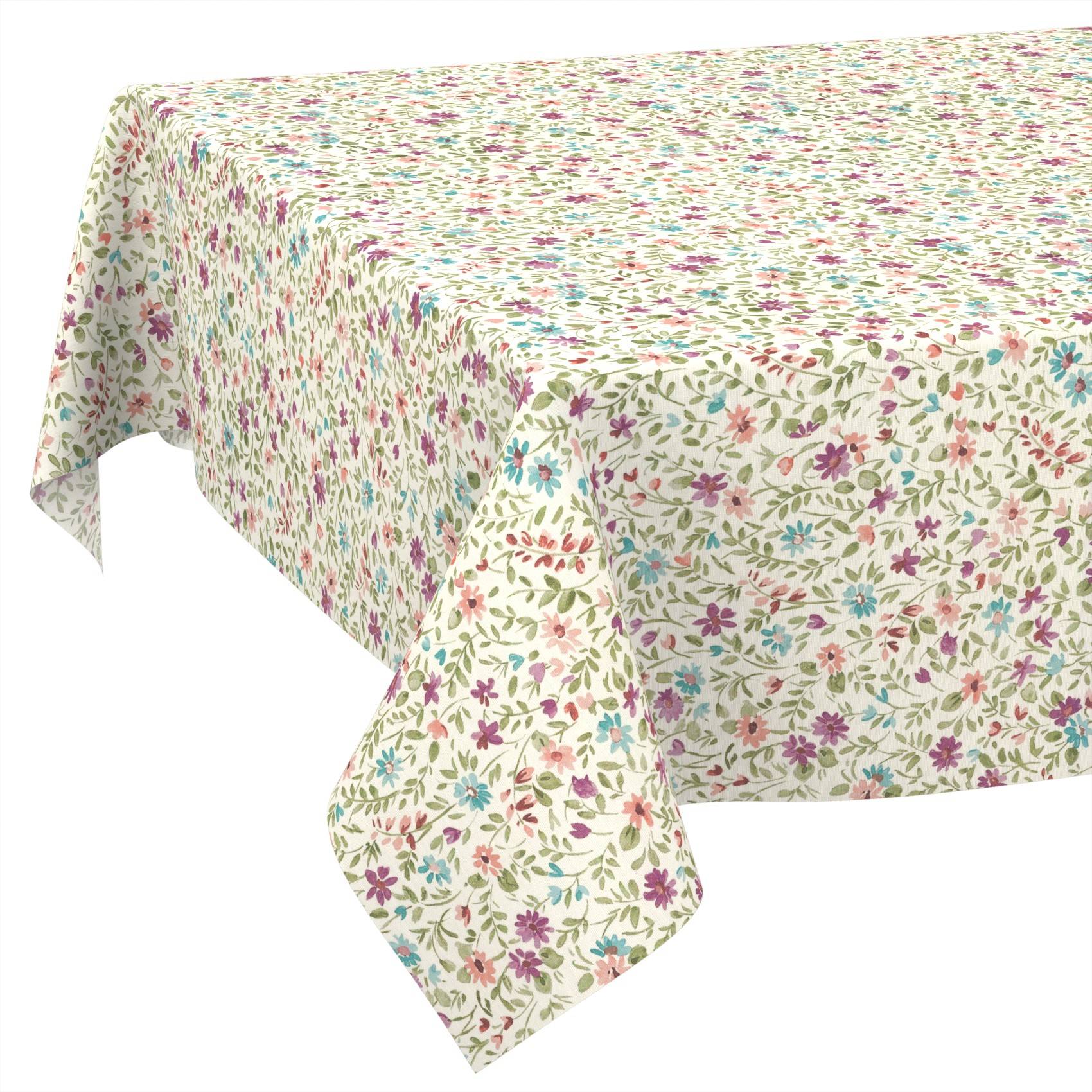 Rechteckiges Tischtuch mit cremefarbenem Hintergrund und kleinem mehrfarbigem Blumenmuster, das über einen Tisch drapiert ist.