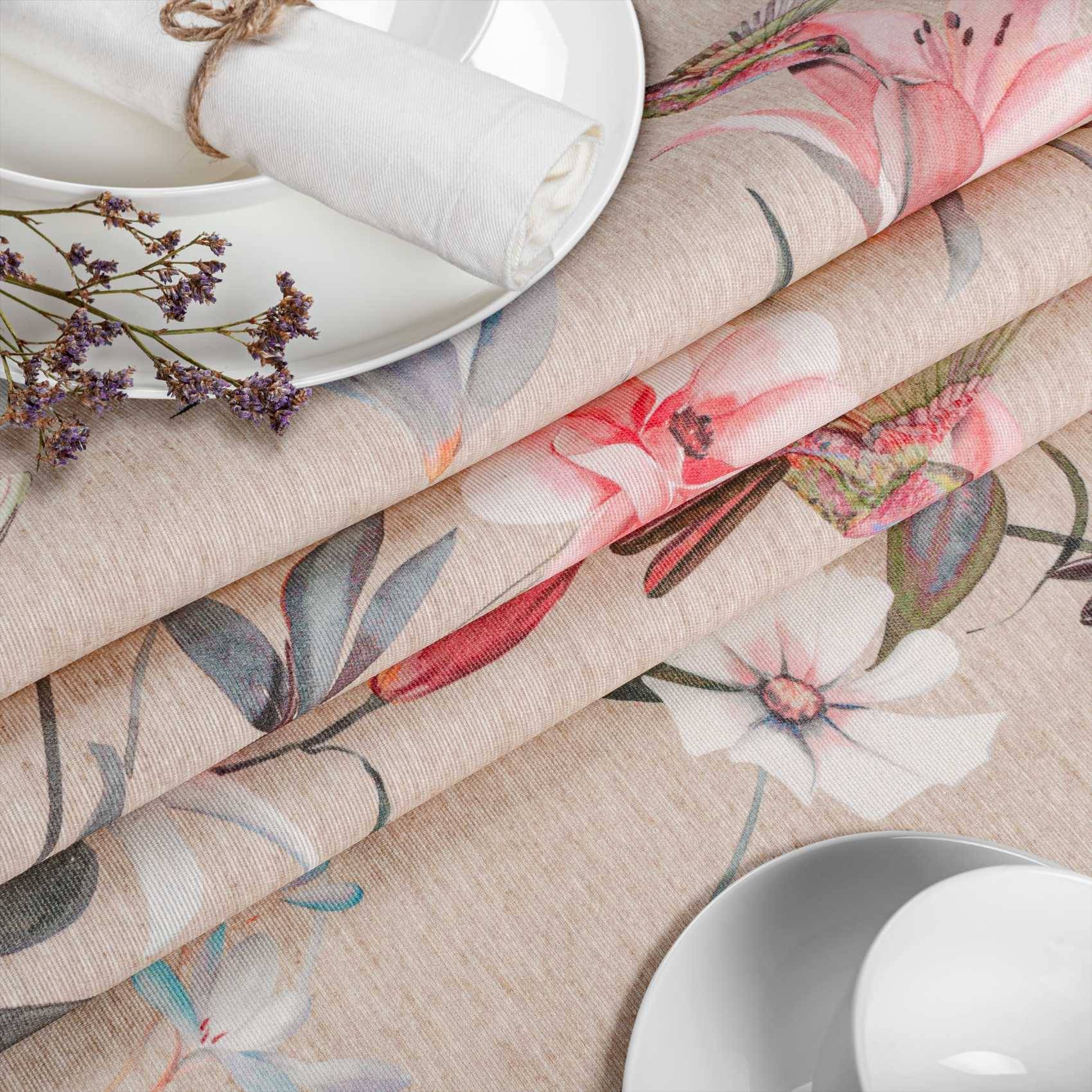 Gefaltete Leinentischdecken mit Blumenmuster, weiße Teller, zusammengerollte Servietten und getrocknete Blumen auf einem hellen Tischgedeck.
