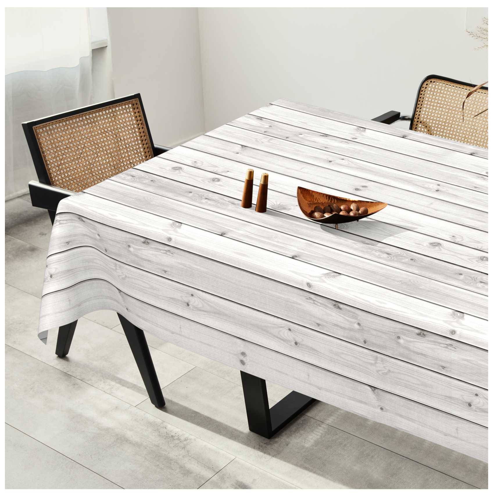 Ein Esstisch mit einer Tischdecke aus hellem Holzbrett, zwei Stühle mit Rohrgeflecht-Rückenlehne und eine kleine dekorative Schale obenauf.