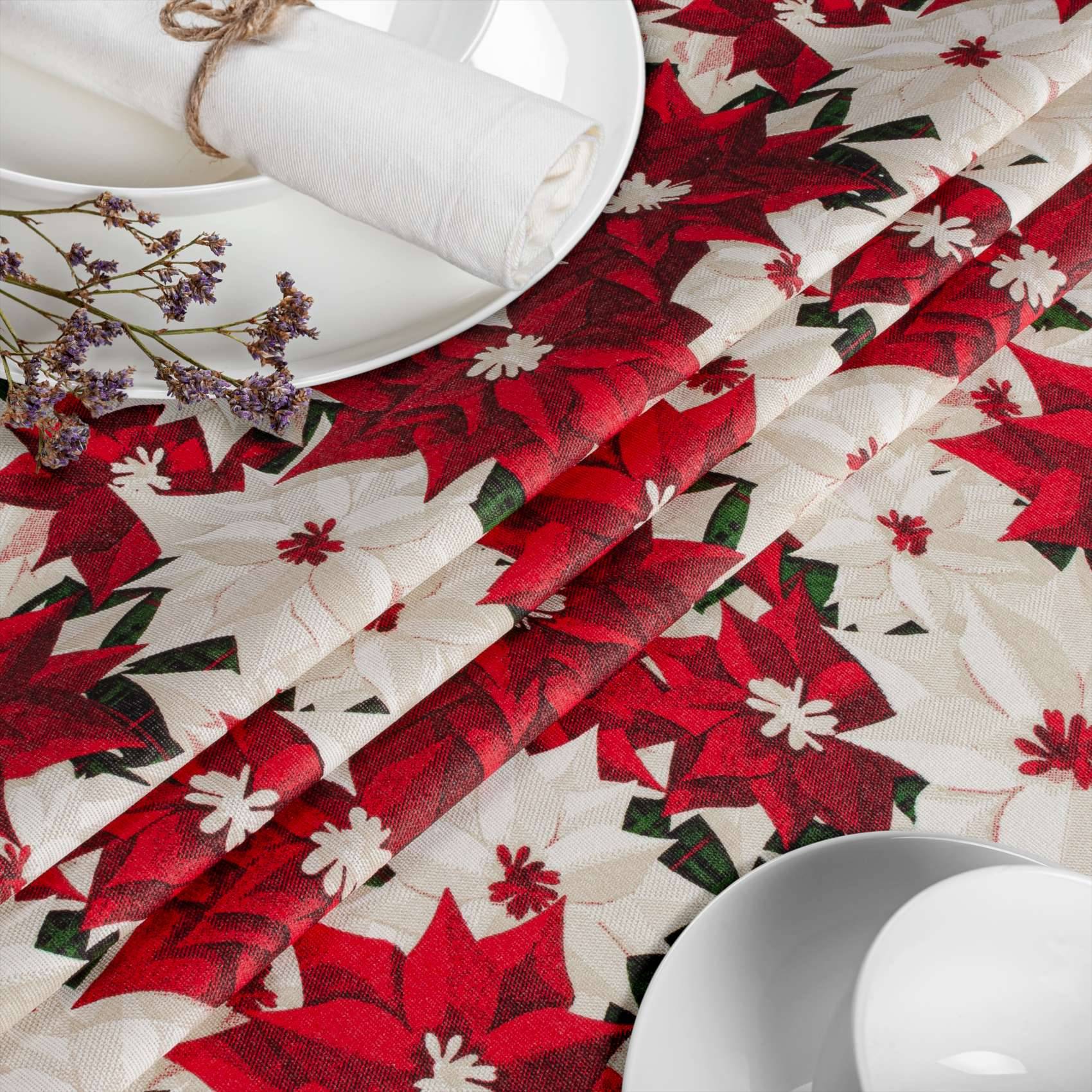Rot-weiß gemusterte Weihnachtsstern-Tischdecke mit weißen Tellern und aufgerollten Servietten, die auf eine festliche Weihnachtstischeinstellung hindeuten.