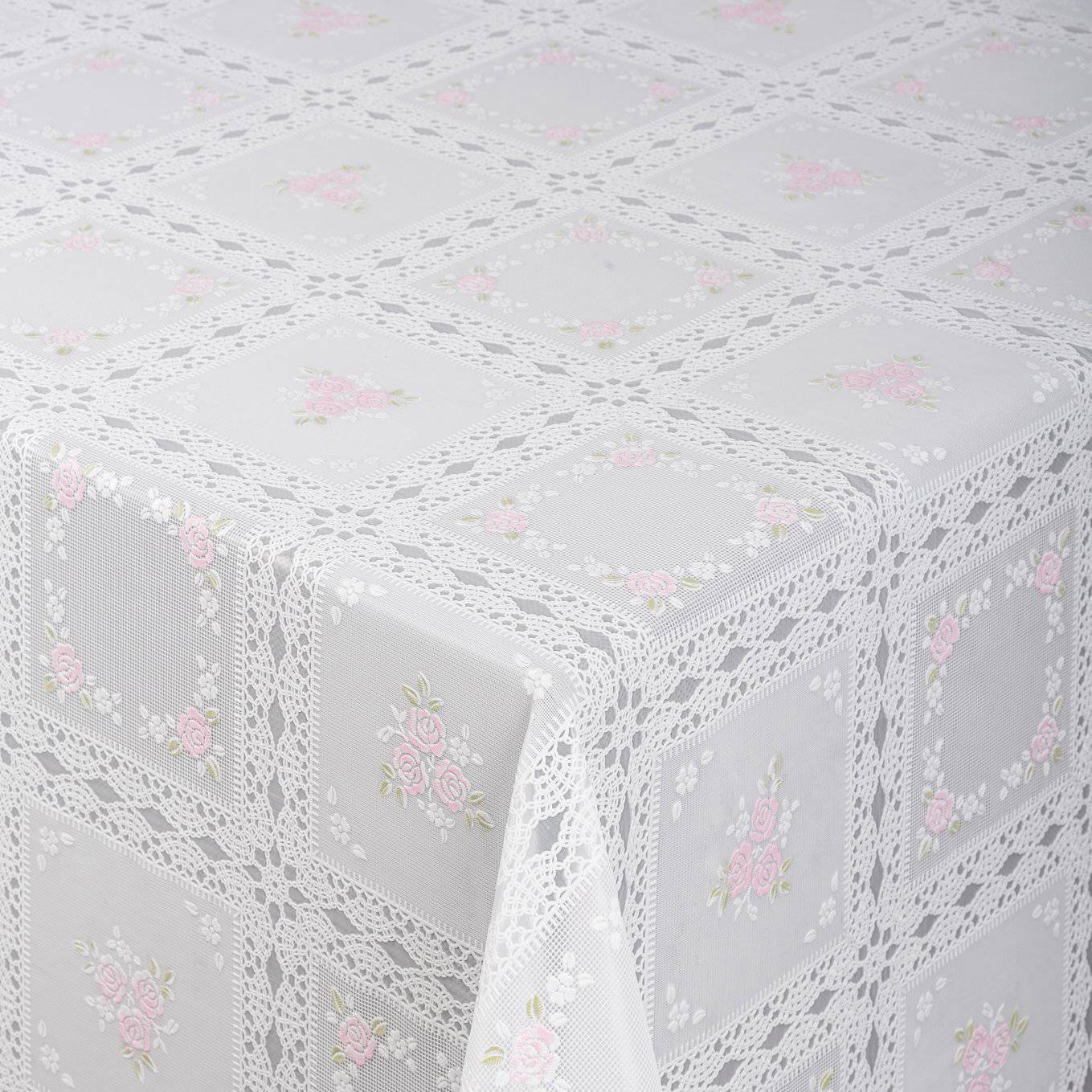 Weiße Spitzentischdecke mit zartem rosa Blumenstickerei, die einen Tisch bedeckt und über die Kante drapiert ist.