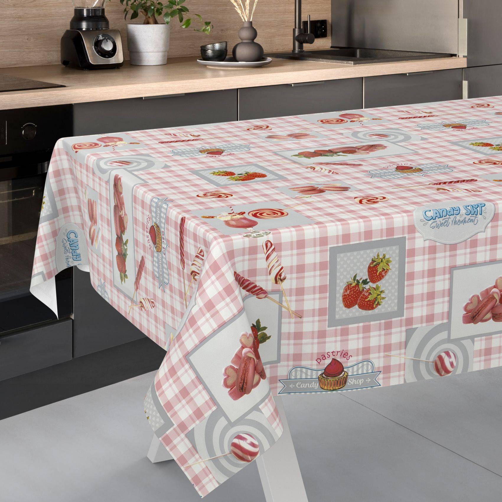 Küchentisch bedeckt mit einer rosa Gingham-Süßigkeitsdruck-Tischdecke mit Erdbeeren, Lollipops und Backwaren.