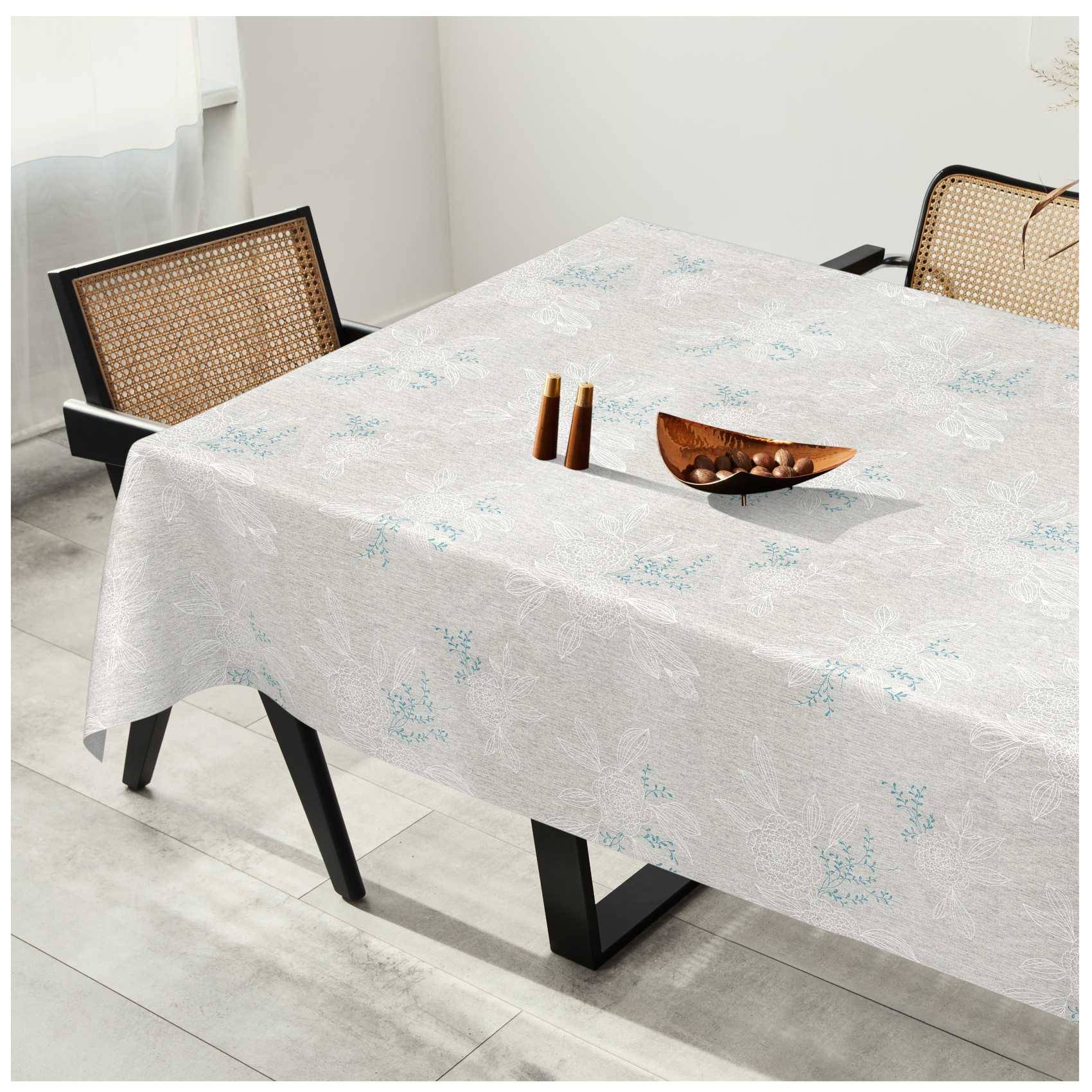 Esstisch mit einer leicht gemusterten Tischdecke, zwei Stühlen mit gewebtem Rückenlehnen und einer Holzschale mit kleinen dekorativen Gegenständen in einem hellen Zimmer.