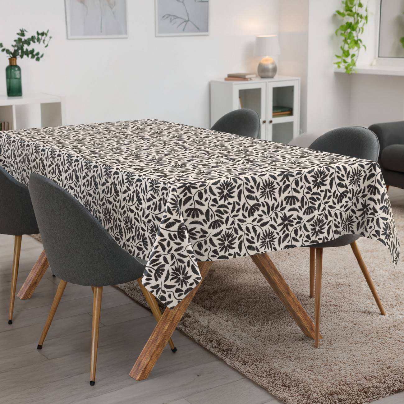 Esstisch mit einer schwarz-weißen gemusterten Tischdecke in einem modernen Wohnzimmer mit grauen Stühlen und einem Teppich.