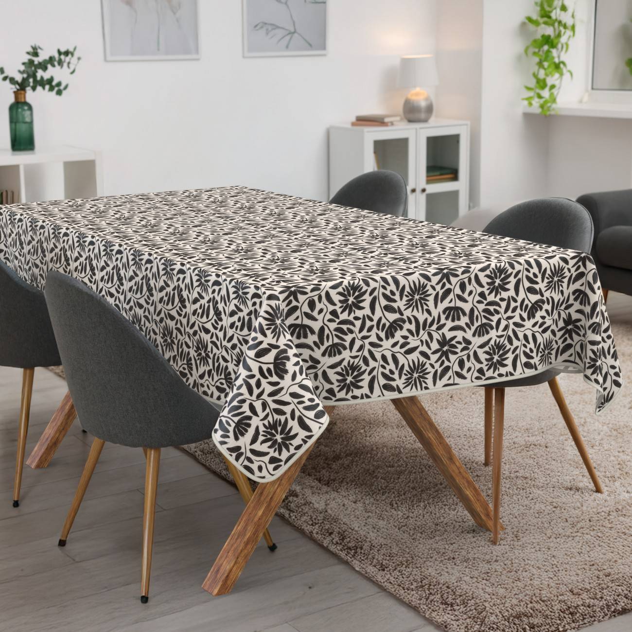 Esstisch mit einer schwarz-weißen Blumententischdecke in einem modernen Wohn-Esszimmer, umgeben von dunklen Stühlen
