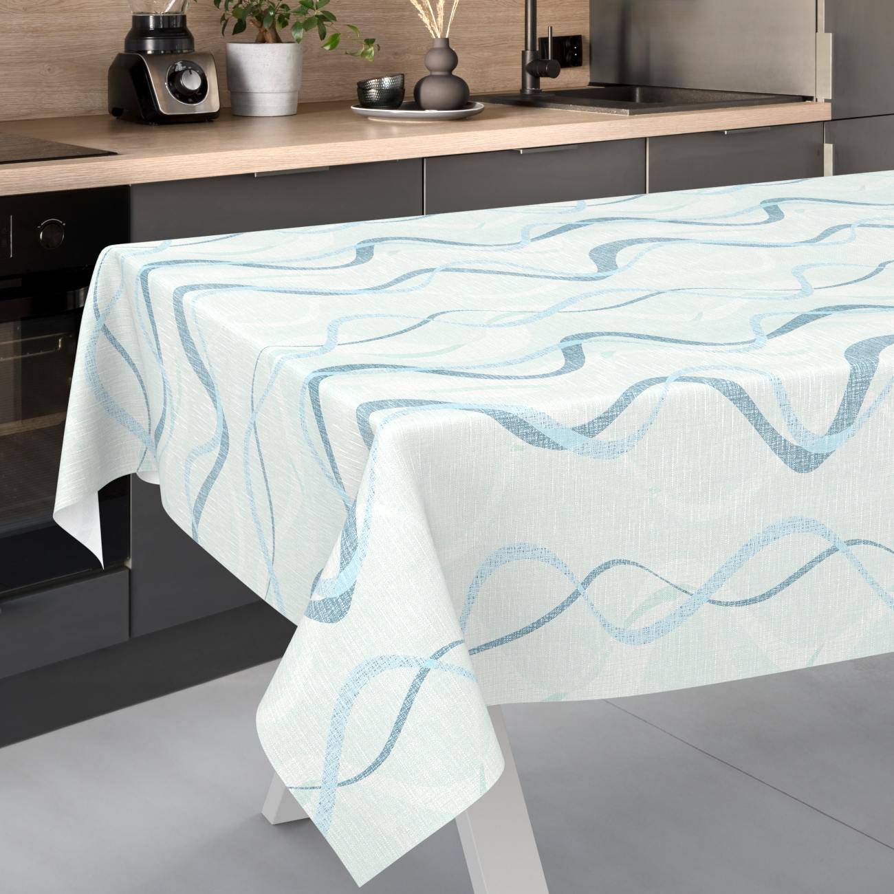 Tisch mit einer hellblauen und weißen, wellenmustrigen Tischdecke in einer modernen Küche.