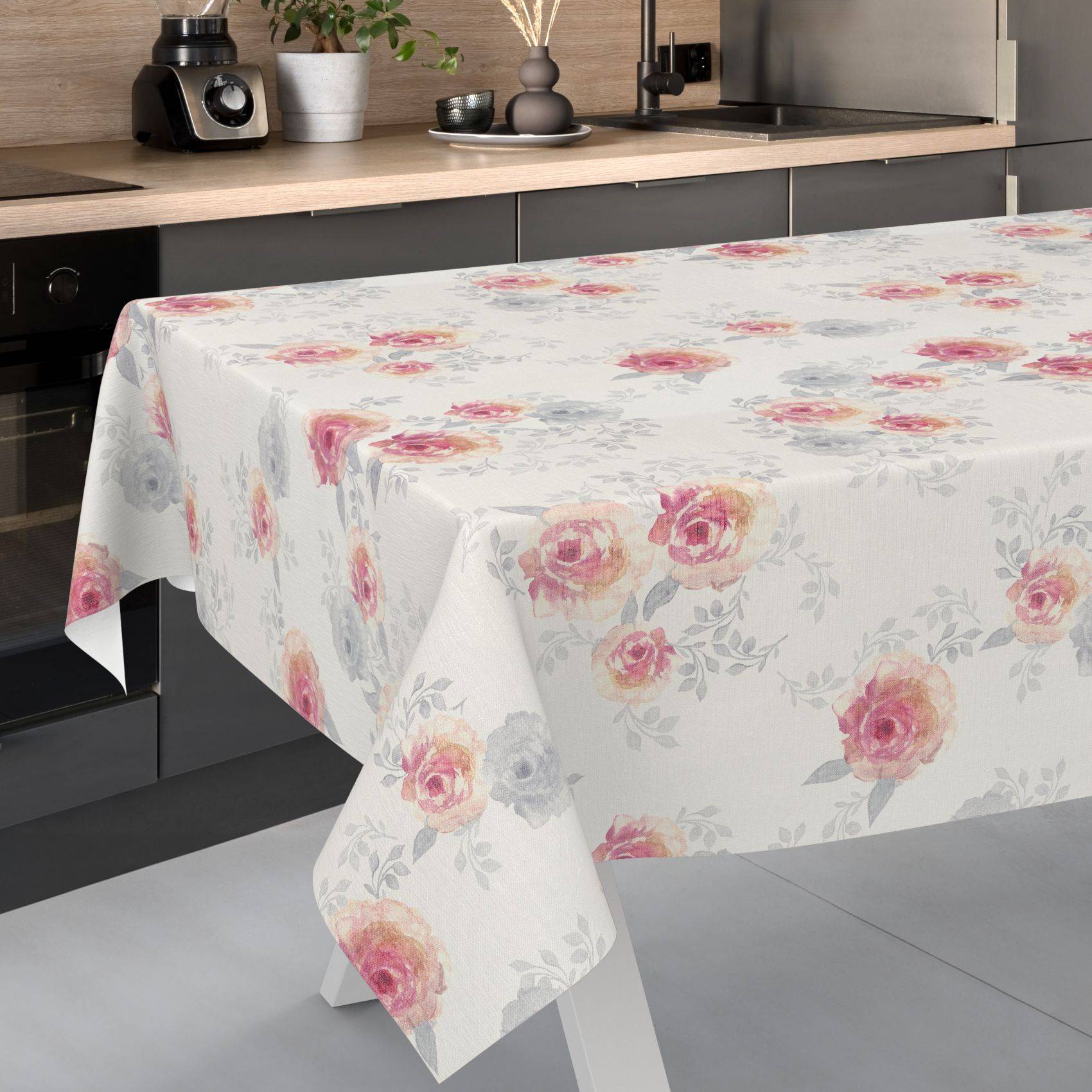 Blumig gemustertes Tischtuch mit rosa und grauen Rosen, das über einen Küchentisch in einer modernen Küche drapiert ist.