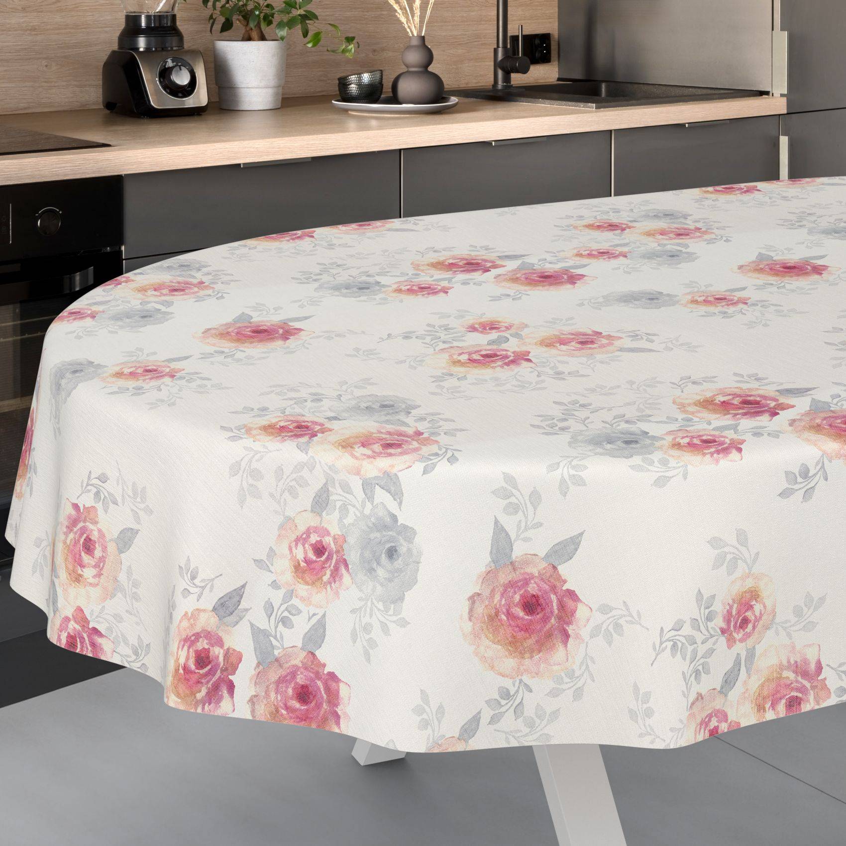 Runder Esstisch mit einer weißen Blumentischdecke mit rosa und grauen Rosen in einer modernen Küche.