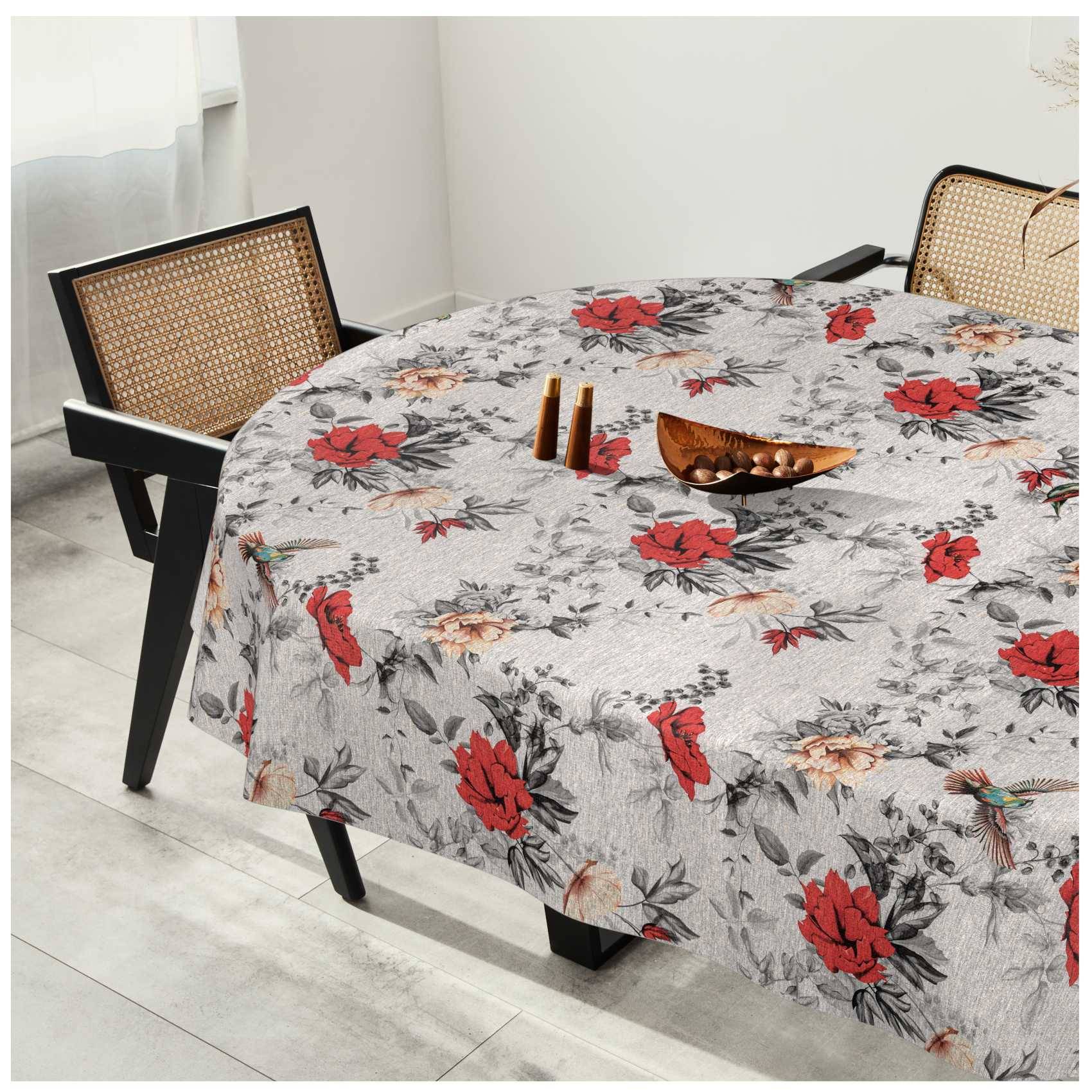Runder Esstisch mit grauer Blumentischschdecke, zwei Stühle mit Rohrgeflecht-Rückenlehne und eine kleine Holzschale oben darauf in einem hellen Raum.