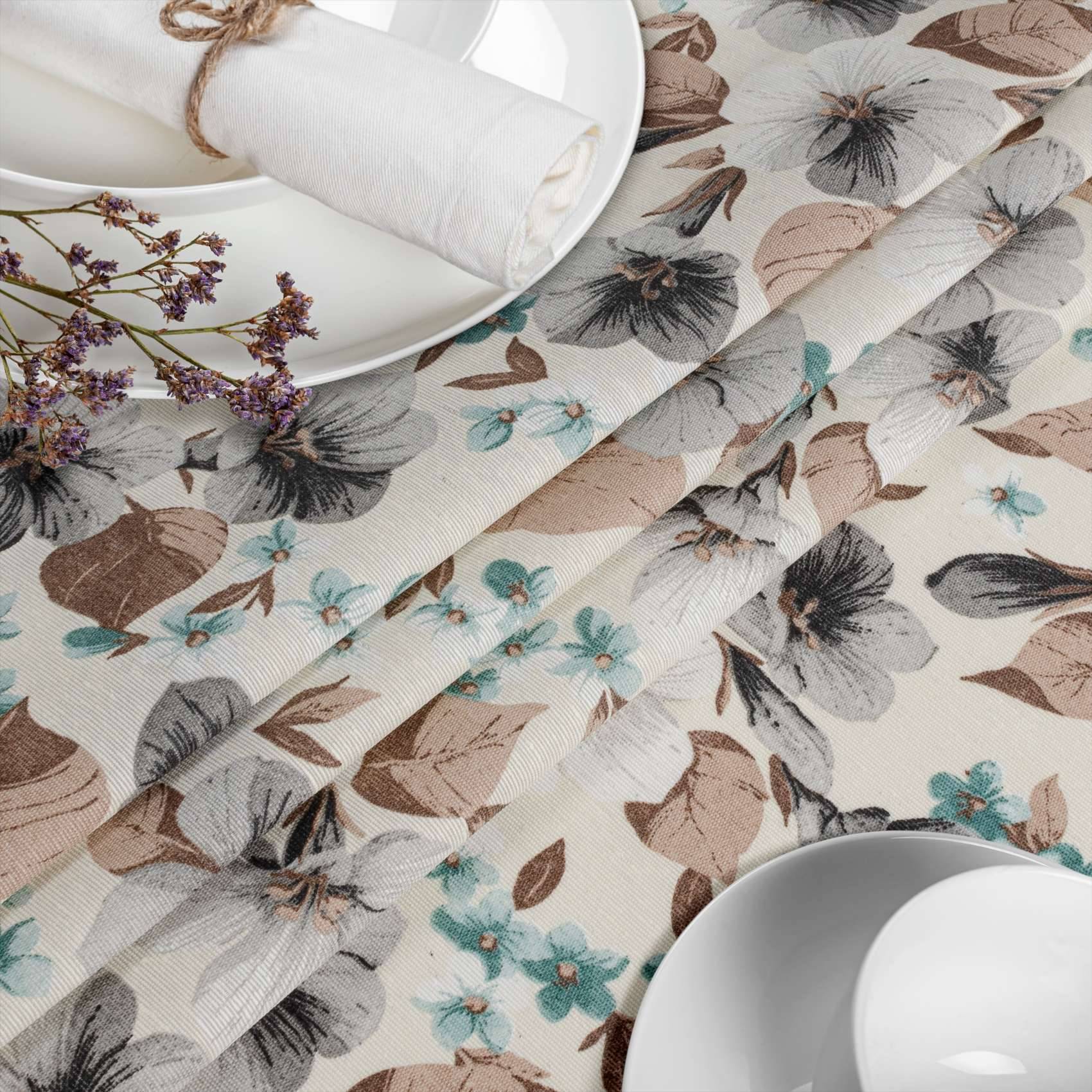 Tischdeckung mit blumenmusterten Tischsets oder Servietten in Beige, Grau und Blaugrün neben weißen Tellern und Tassen