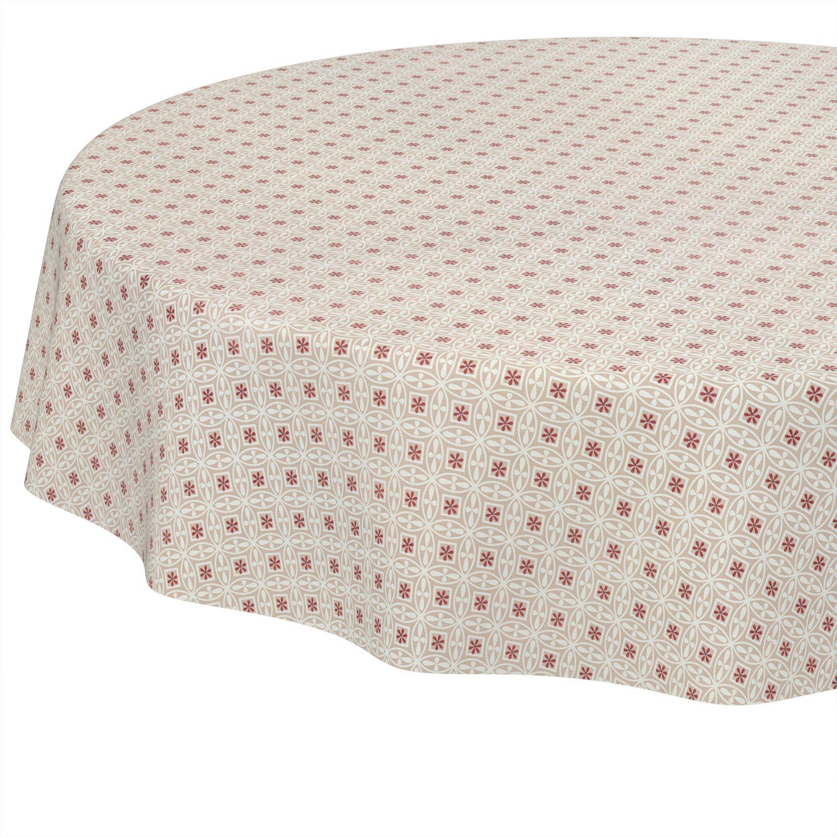 Runder Tisch mit einer beigefarbenen gemusterten Tischdecke mit kleinen roten Blütenmotiven.