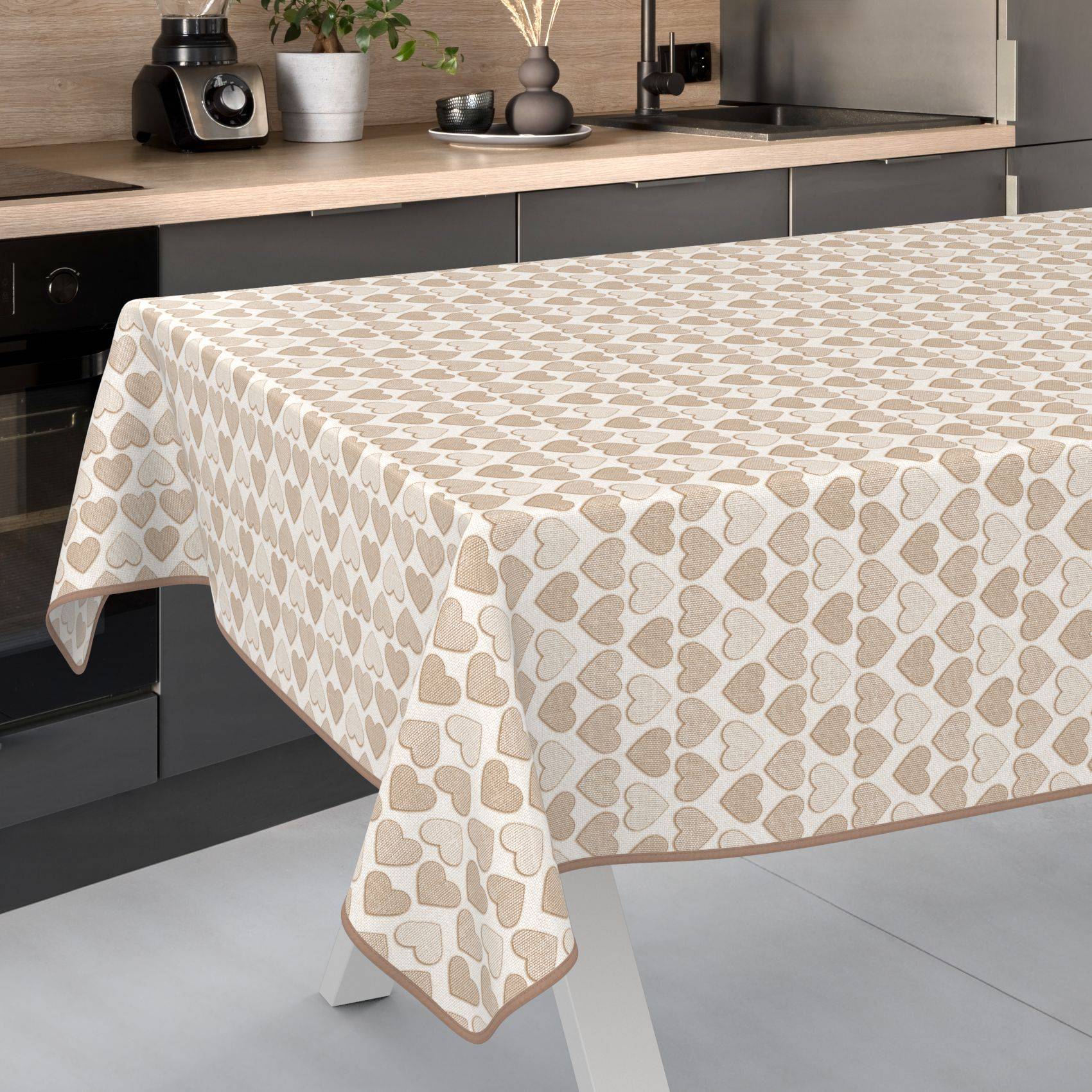 Beigefarbige Tischdecke mit Herzenmuster, die über einen Esstisch in einer modernen Küche drapiert ist.