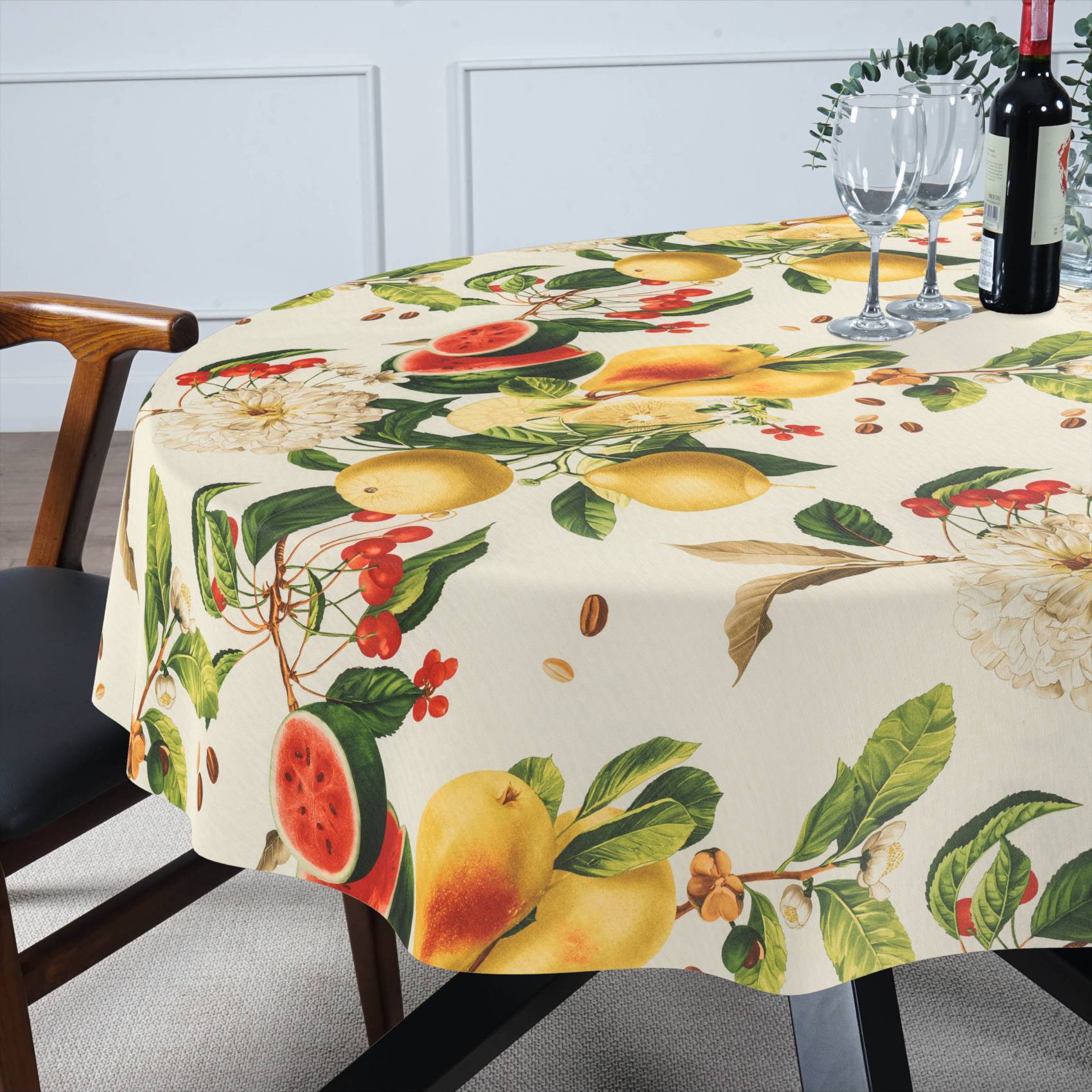 Runder Tisch mit einer Tischdecke mit Fruchtmuster, gedeckt mit Weingläsern und einer Flasche in einem Esszimmer.