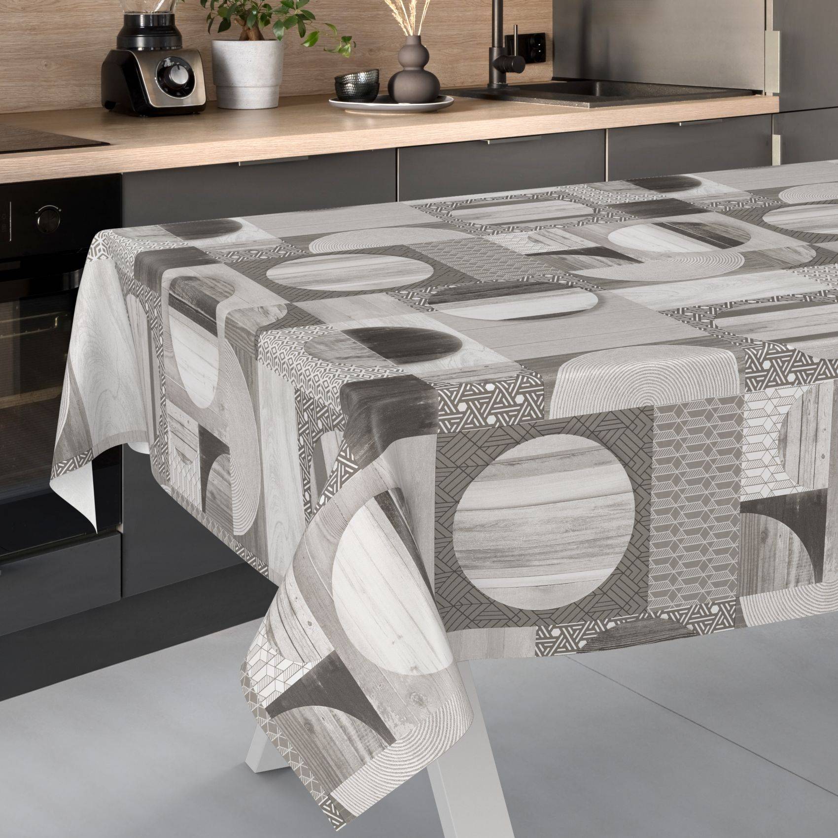 Küchentisch mit einer grau gemusterten geometrischen Tischdecke, vor einer modernen Arbeitsplatte und Schränken.